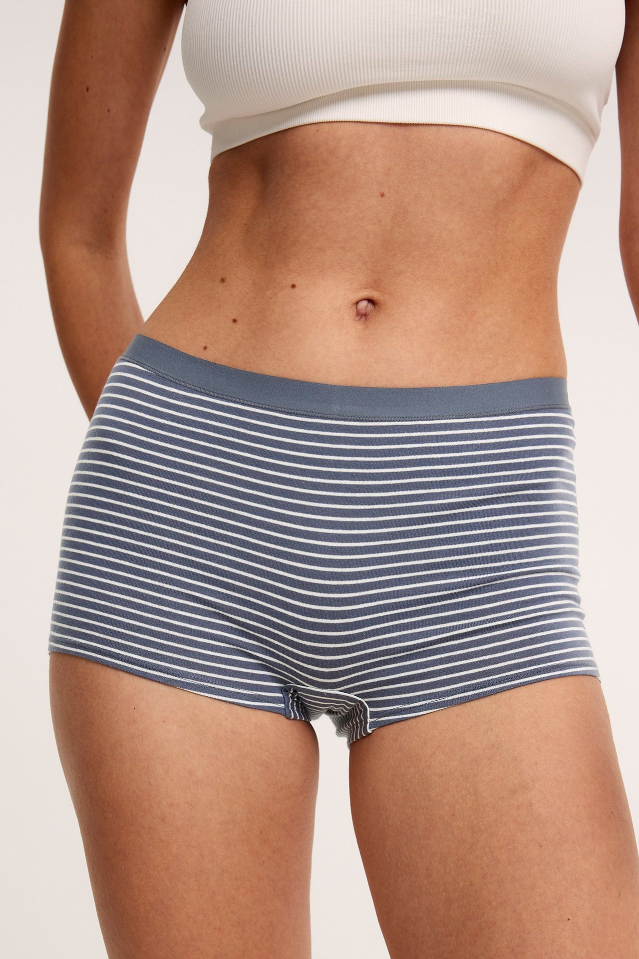 Widok z przodu: kobieta w szaro-białych bawełnianych bokserkach w paski i białym prążkowanym biustonoszu.