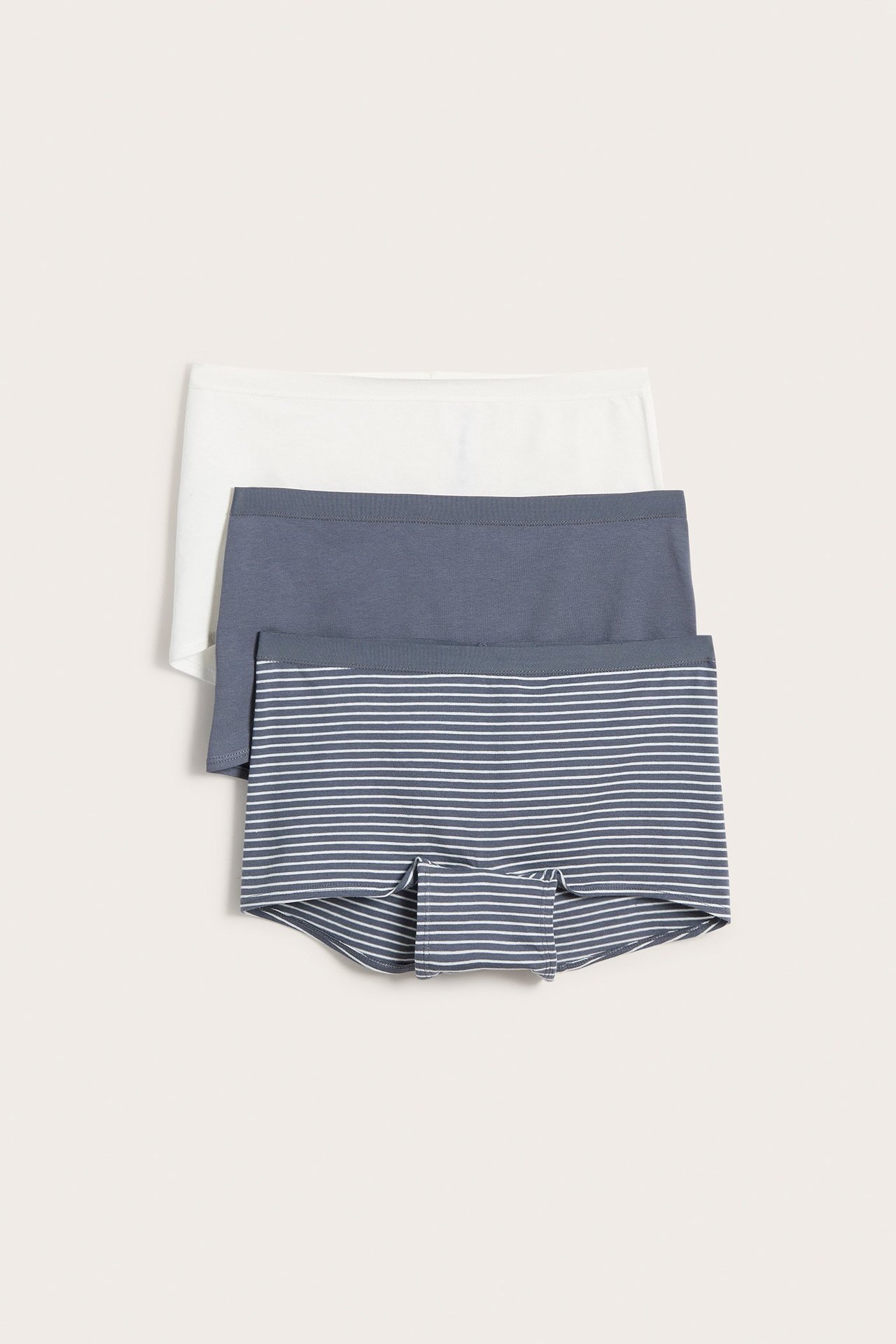 Widok z przodu trzech damskich bokserek: białych, jednolitych szarych i szarych w białe paski.