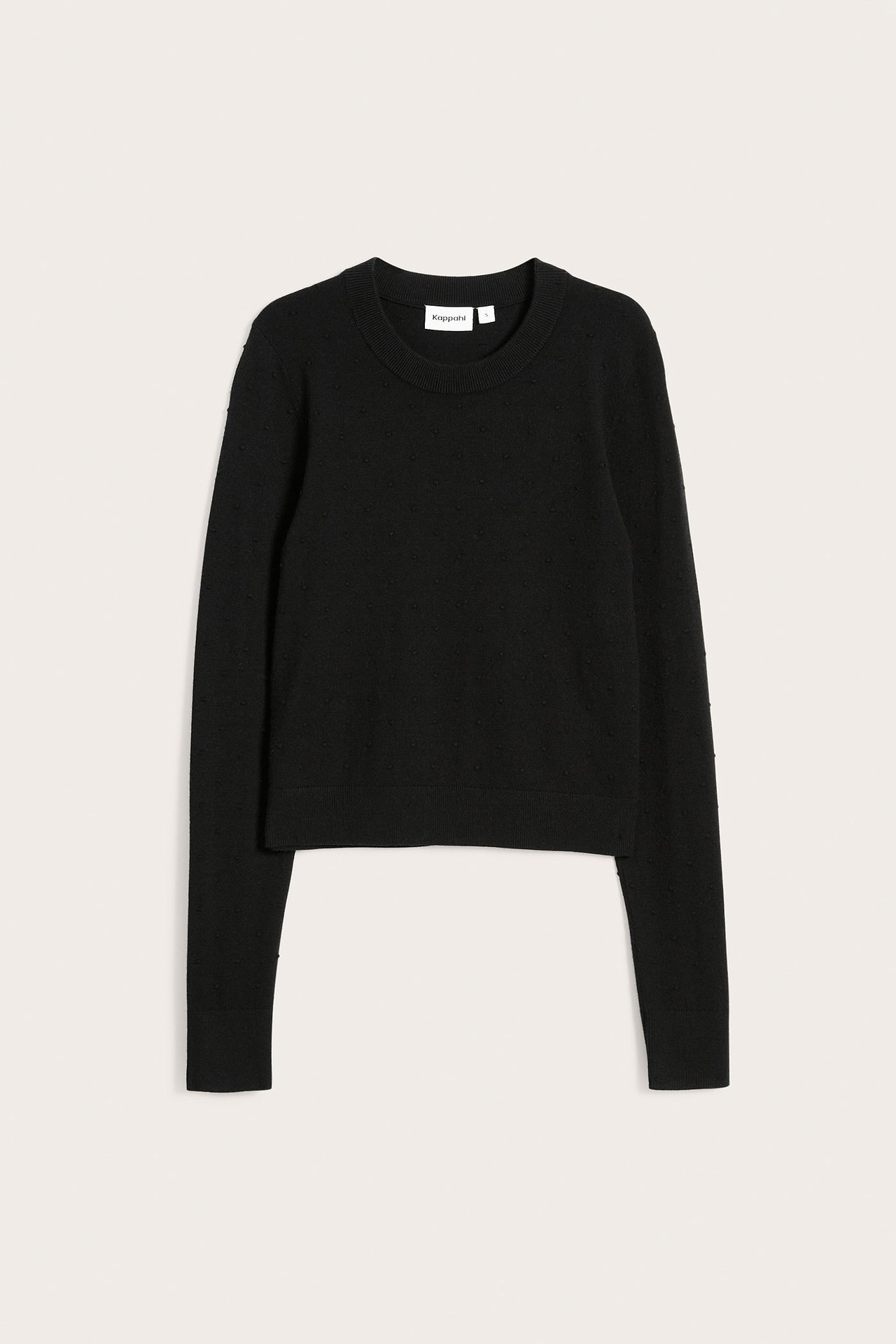 Edestäpäin, musta neulepusero hienovaraisella pilkkukuviolla ja pyöreällä pääntiellä.