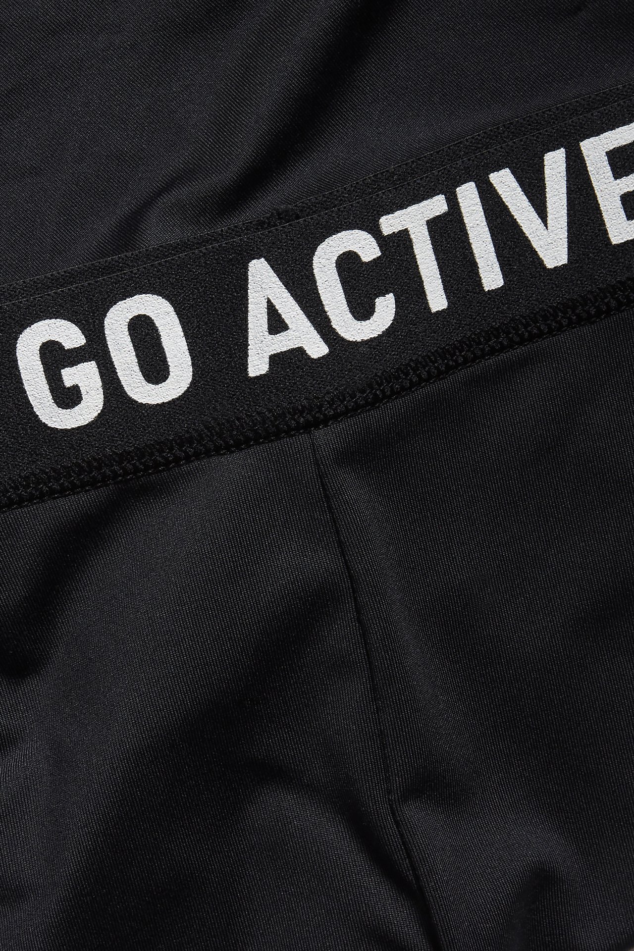 Zbliżenie czarnych spodenek rowerowych z białym elastycznym pasem "GO ACTIVE".