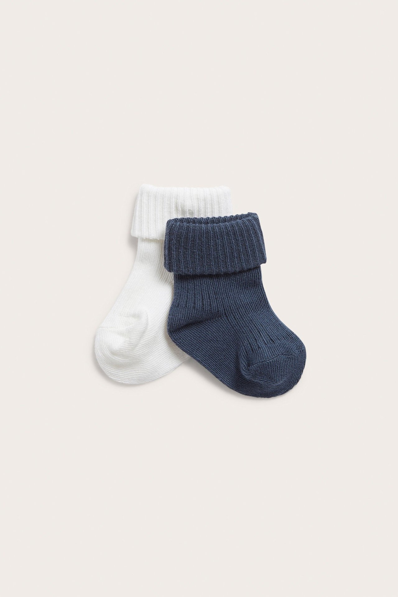Forfra, to ribbestrikkede babysokker, en mørkeblå og en hvit, med brettede kanter.