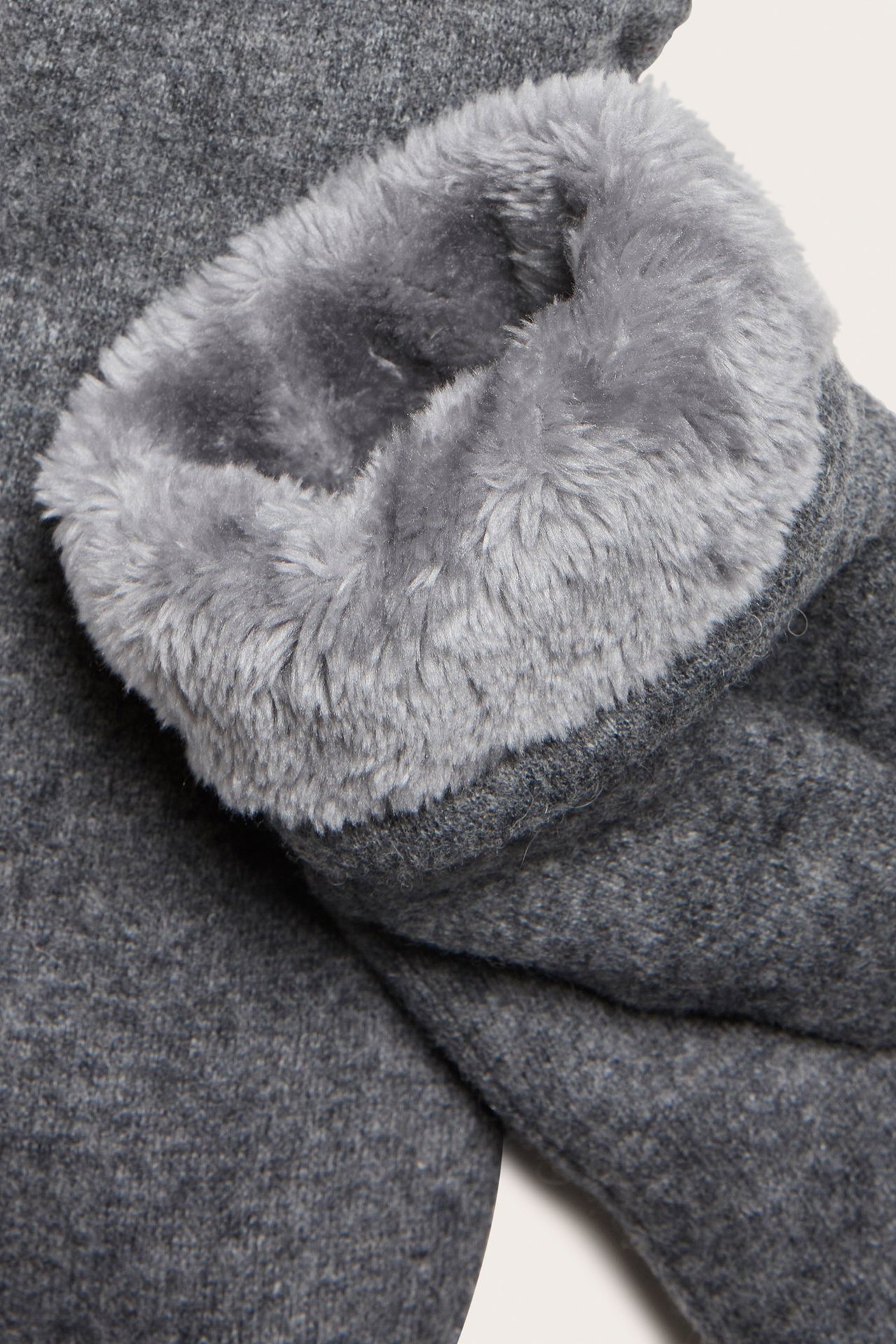 Zbliżenie szarej rękawicy z wełny z miękką szarą podszewką z misia.