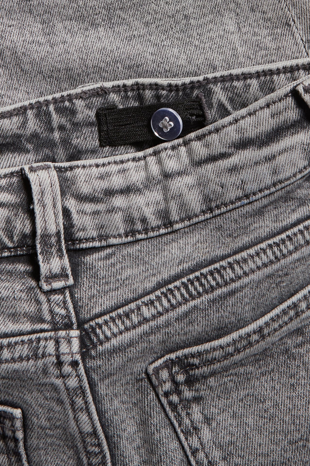Zbliżenie na dziecięce jeansy z przetartego czarnego denimu z widocznym zatrzaskiem.