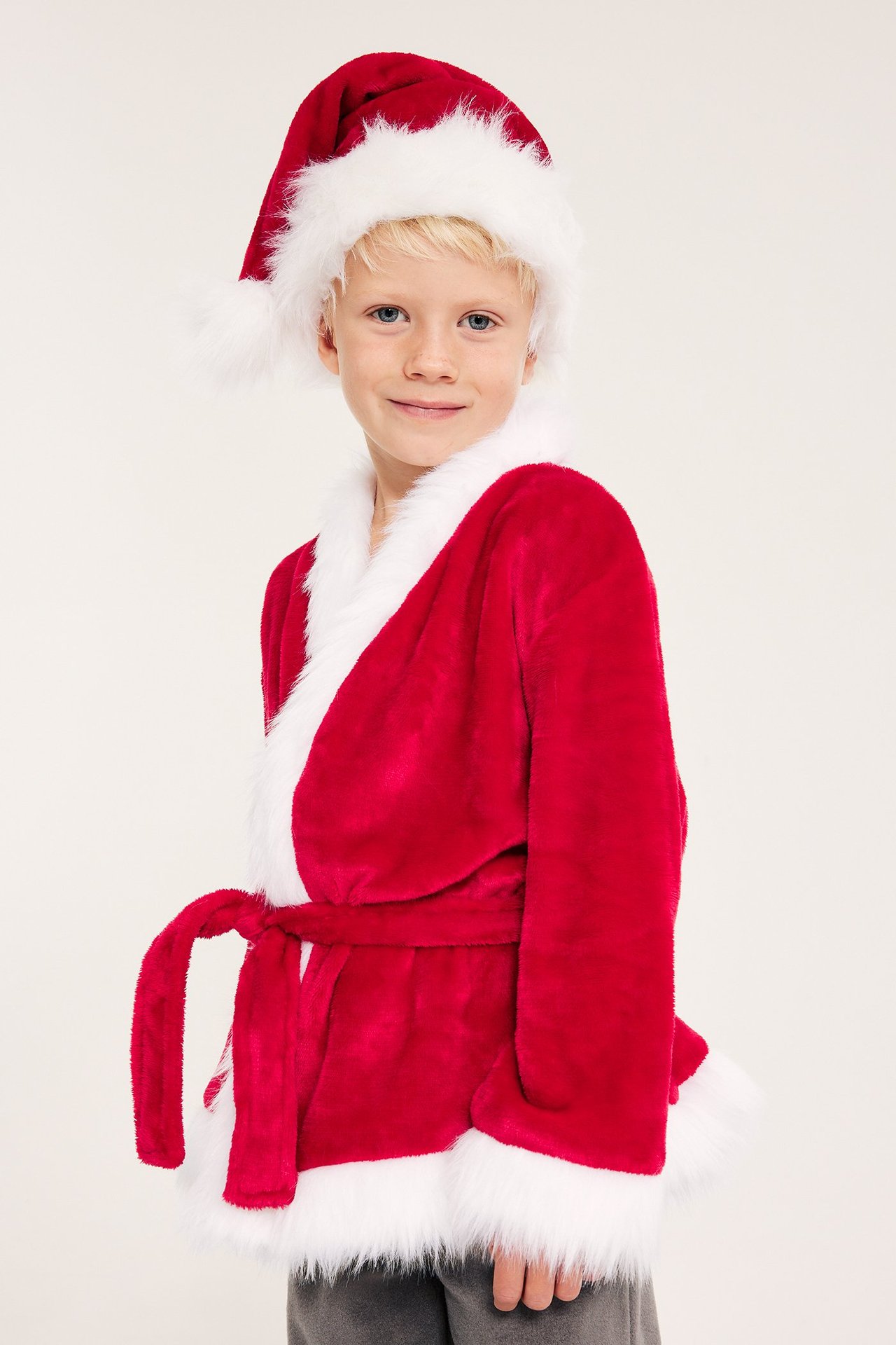 Barn i rød fleece-nissekostyme med hvit faux-fur detaljer, for- perspektiv.