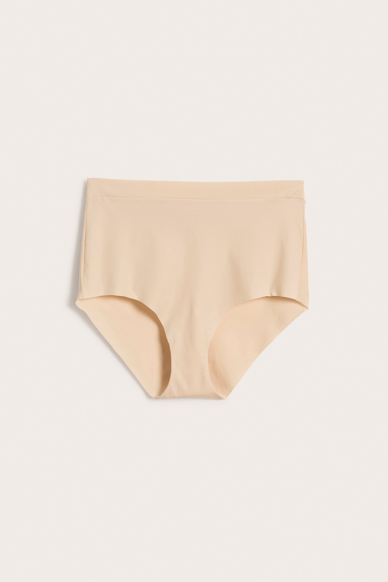 Frontvisning av beige sømløs hipstertruse i mikrofiber med elastisk linning.