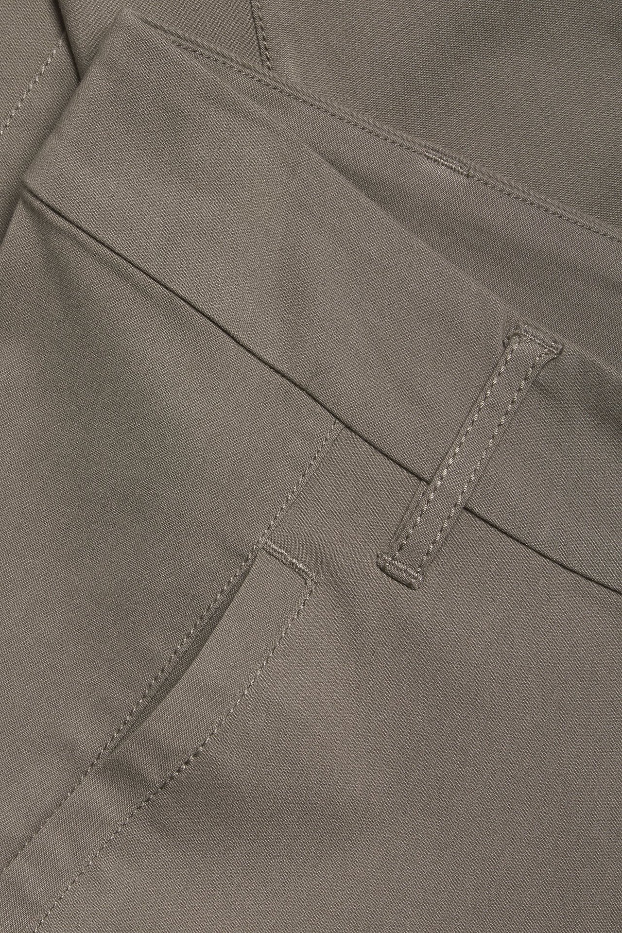 Zbliżenie na brązowe spodnie boyfriend slim fit, ukazujące fakturę materiału, szwy i szlufkę.