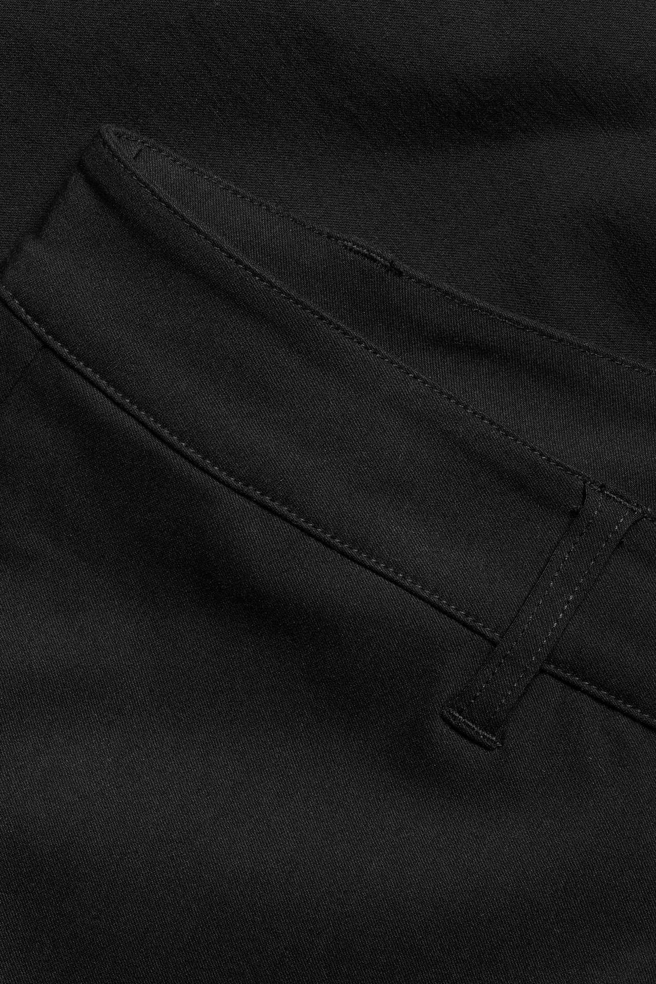 Zbliżenie czarnych spodni bootcut z widocznymi szwami i szlufką na pasek.