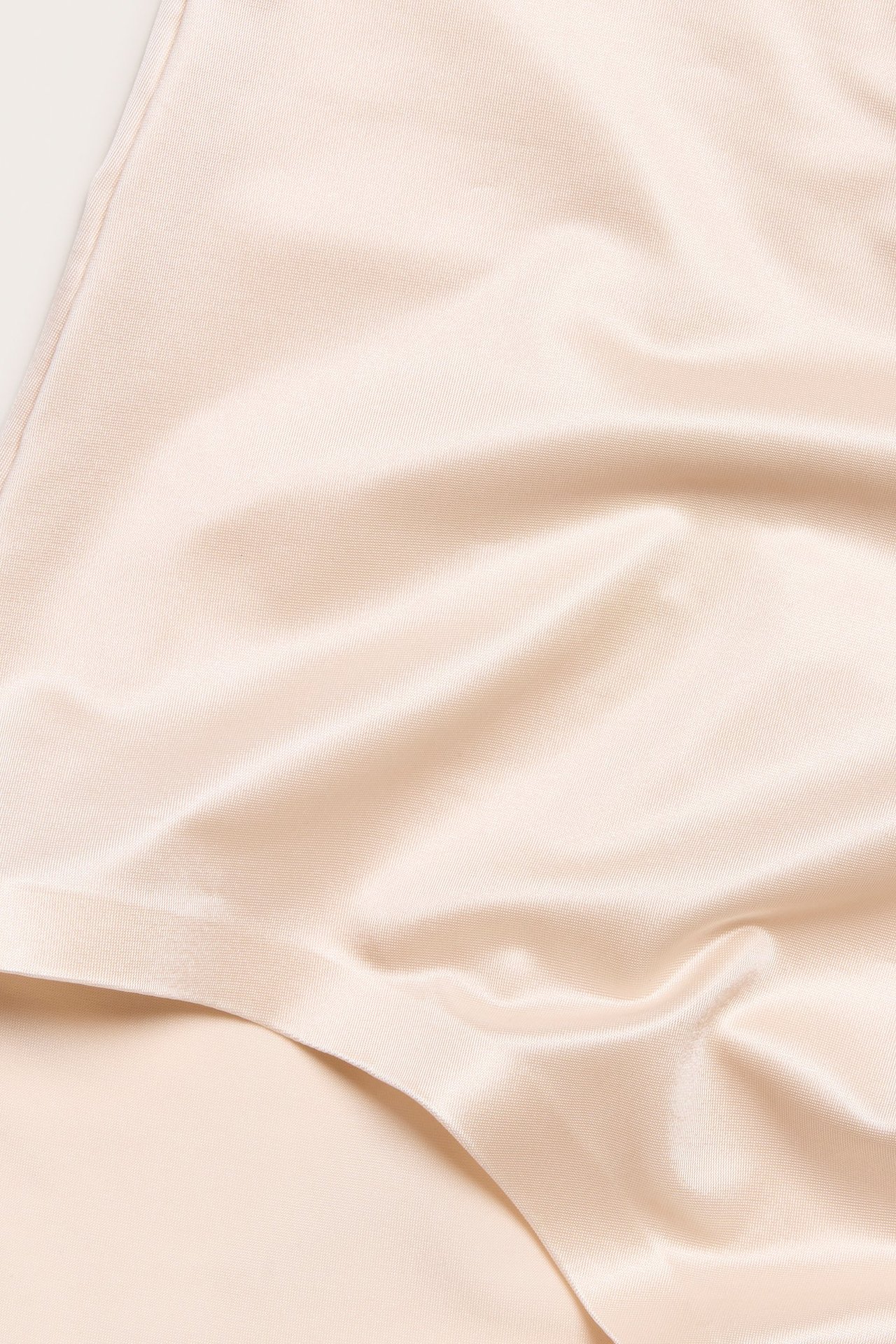 Zbliżenie beżowych majtek modelujących z gładkiej, lekko błyszczącej satynowej mikrofibry.