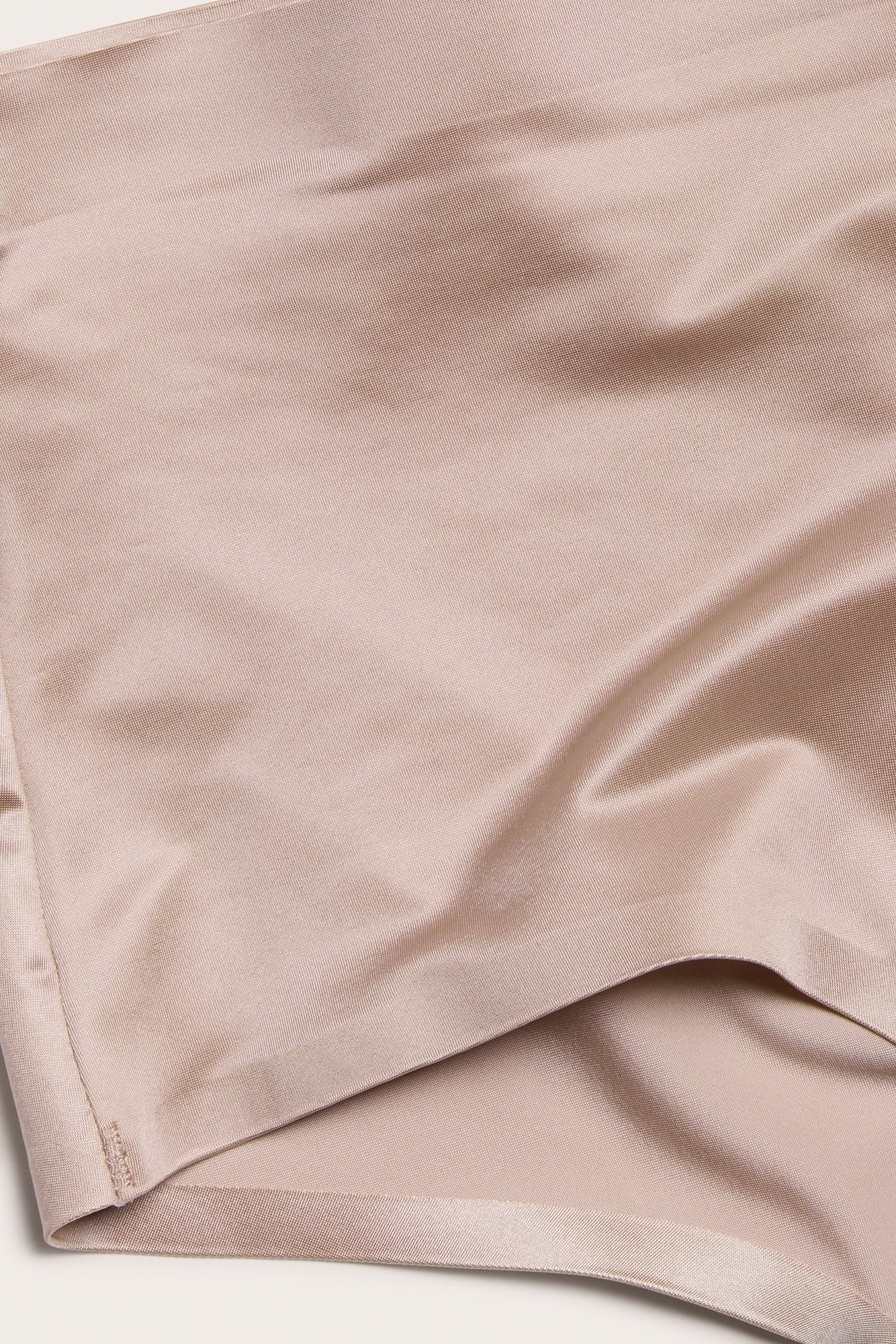 Zbliżenie różowego materiału stringów z satynowej mikrofibry, ukazujące jego gładką, lekko błyszczącą fakturę.