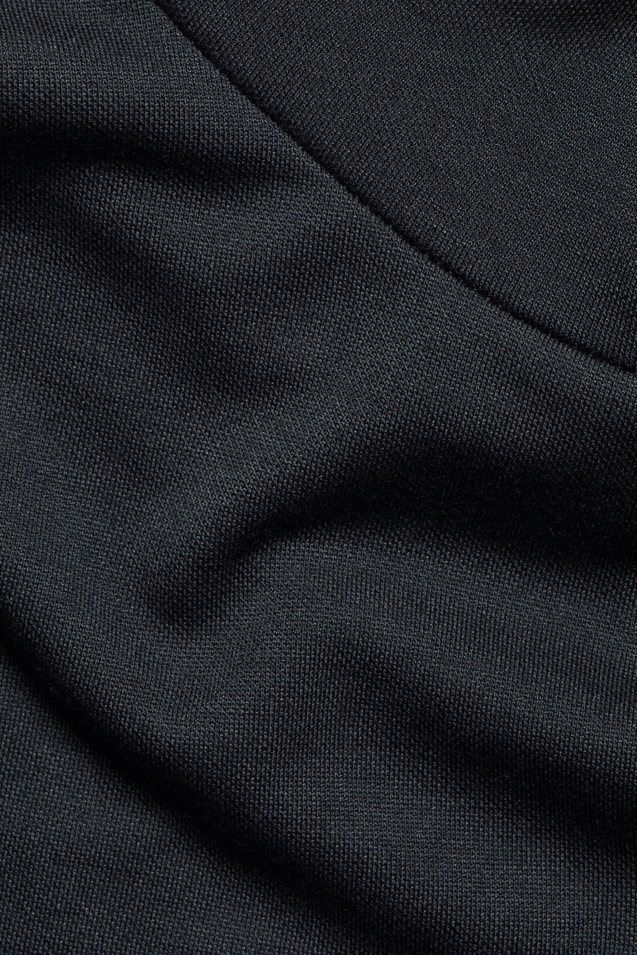 Zbliżenie czarnego materiału z modalu i poliestru krótkiego topu polo z widocznym szwem.