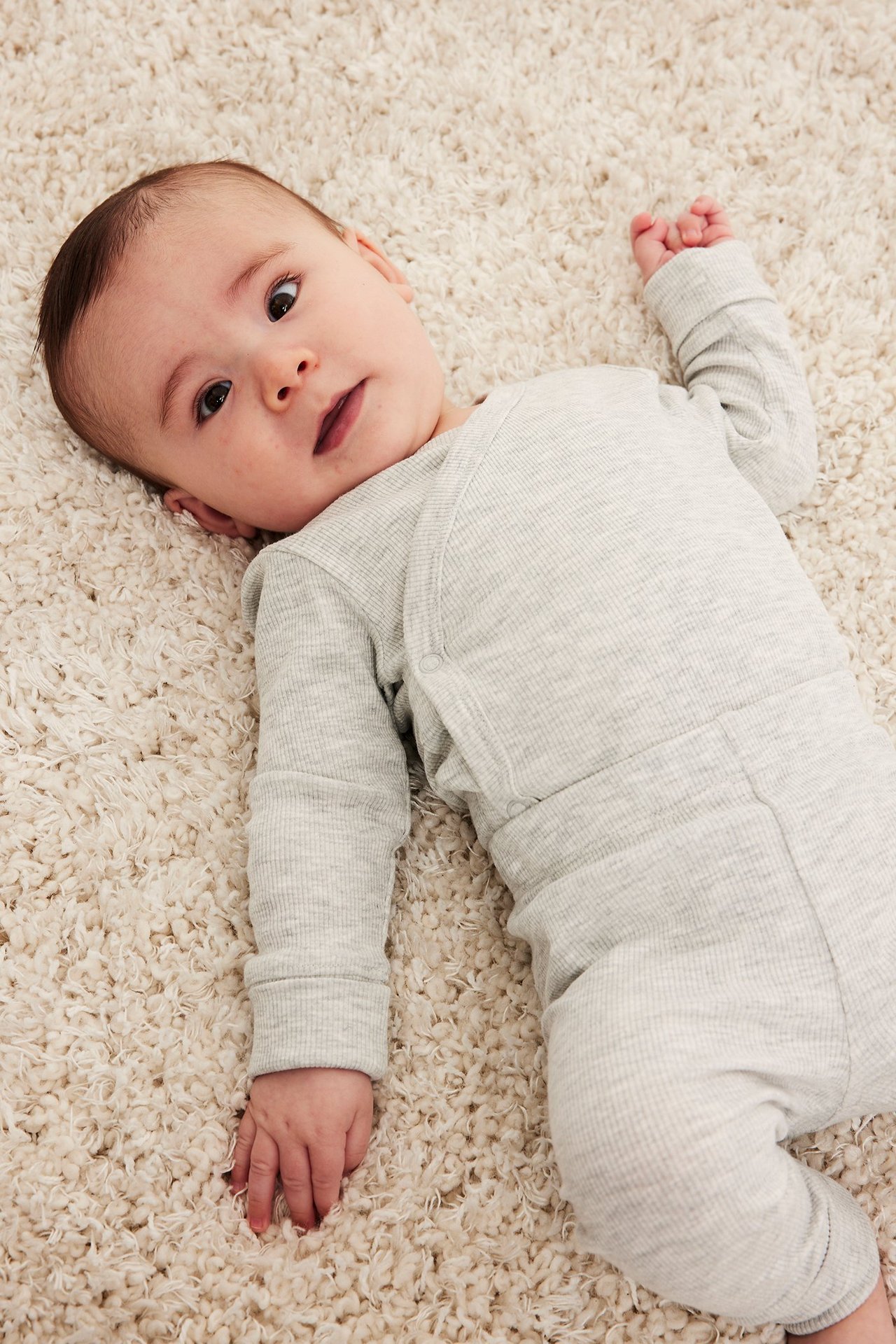 Ylhäältä kuvattu vauva yllään vaaleanharmaa ribattu kietaisubody neppareilla.