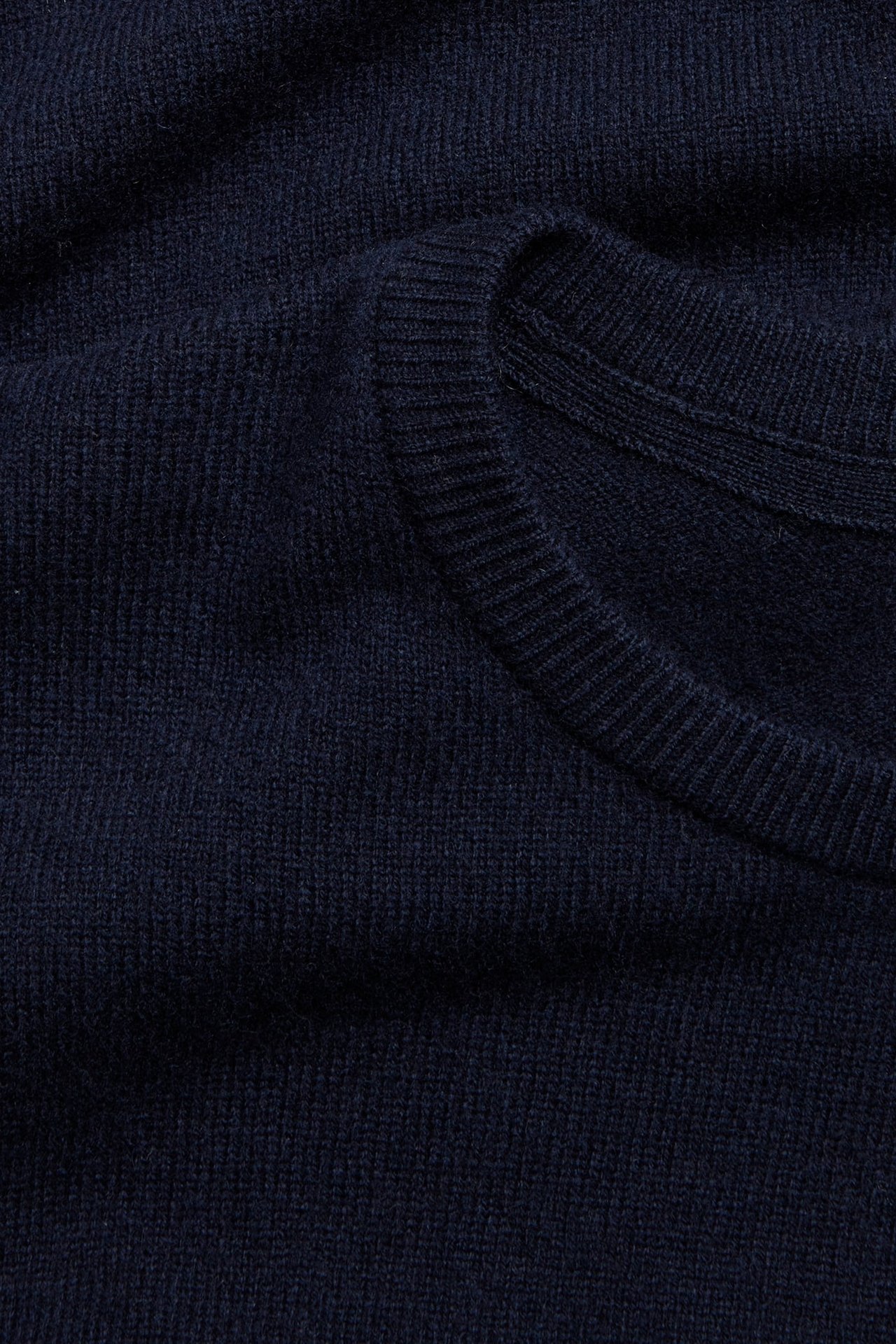 Zbliżenie na granatowy sweter z dzianiny z prążkowanym dekoltem.