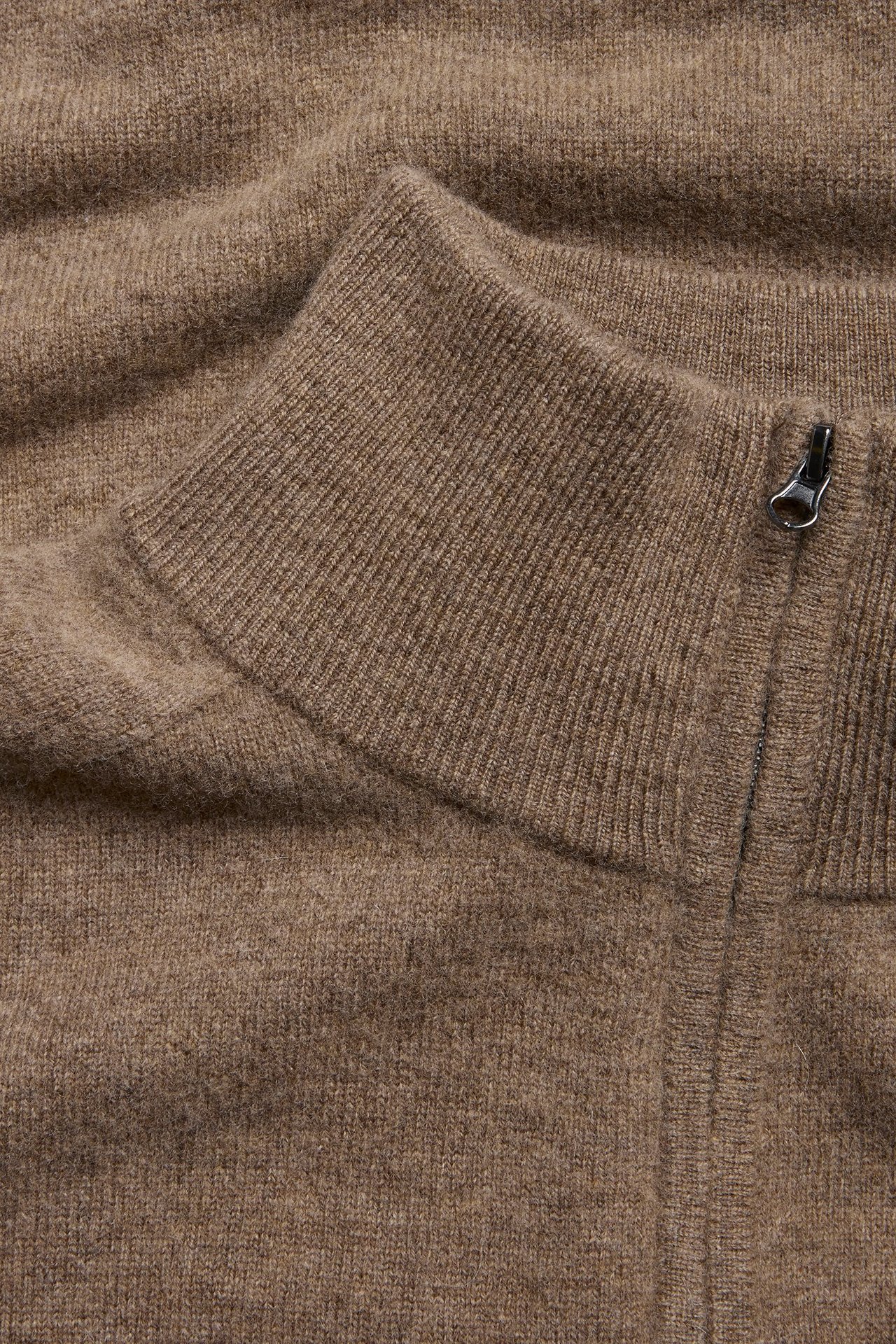 Zbliżenie na brązowy melanżowy sweter wełniany z półgolfem, prążkowanym kołnierzem i zamkiem.