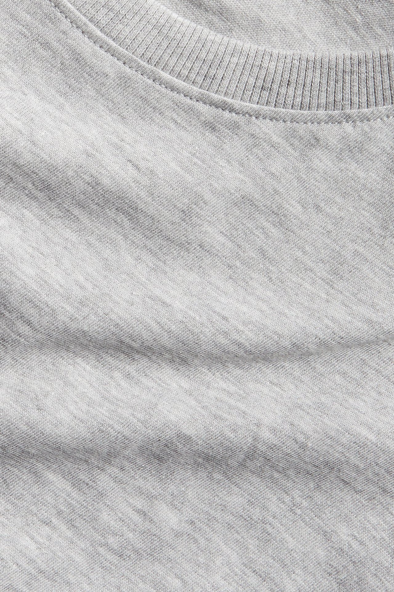Närbild av en ljusgrå melerad t-shirt med ribbad halsringning.