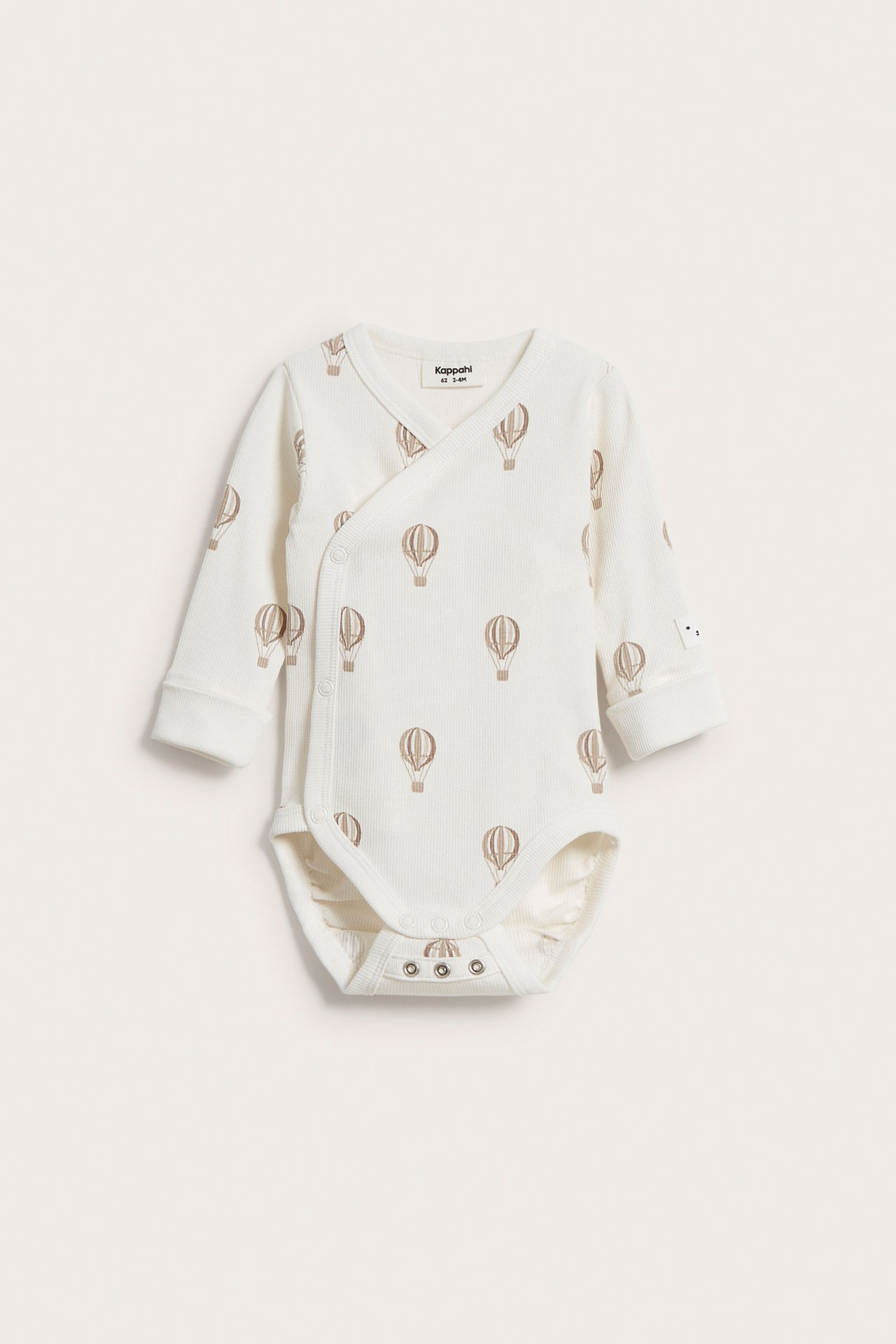 Edestä: beige ribattu vauvan body, jossa kietaisukiinnitys, pitkät hihat, kuumailmapallokuvio ja nepparit.