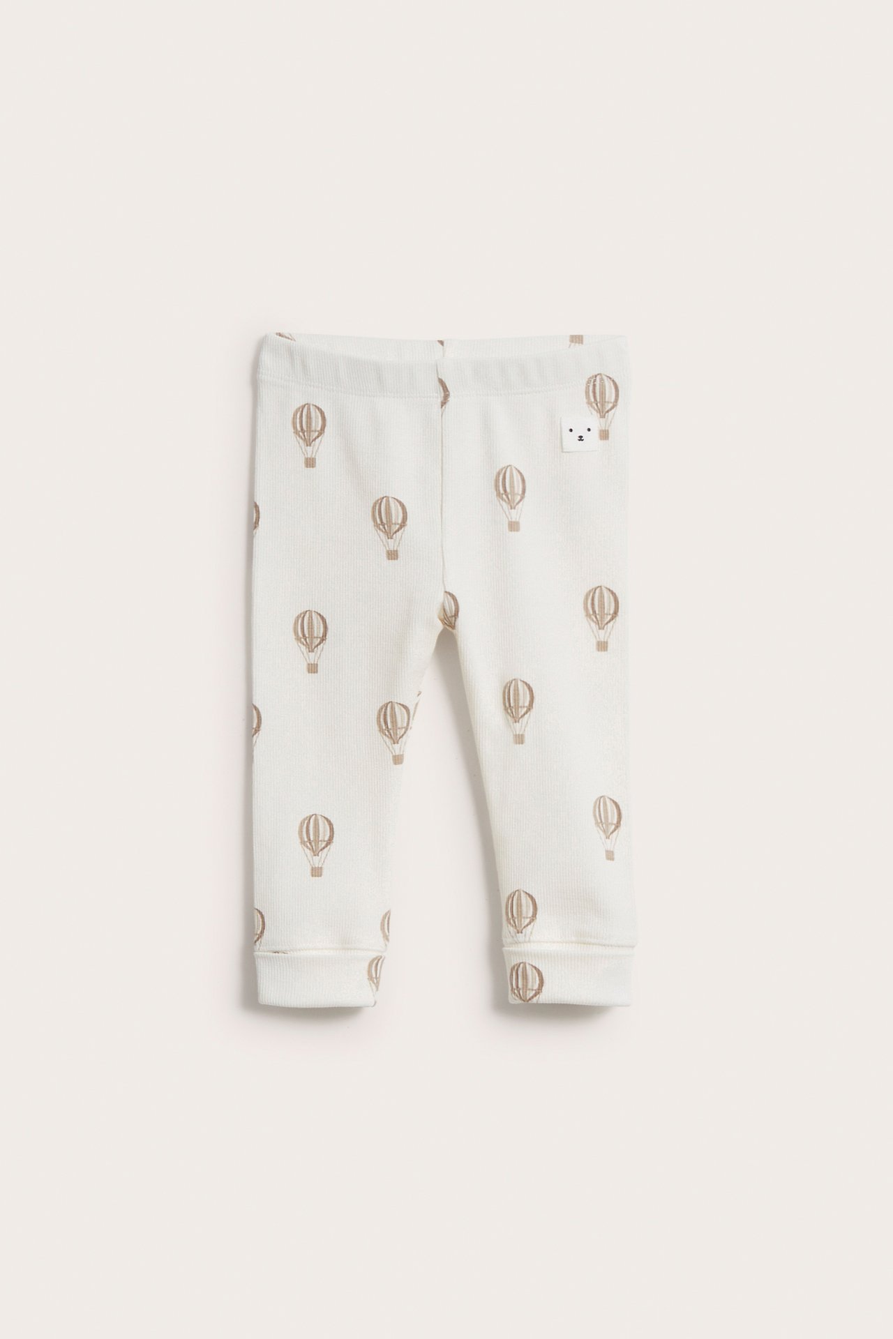 Framifrån: beiga ribbade baby-leggings med brunt luftballongsmönster och resår i midjan.