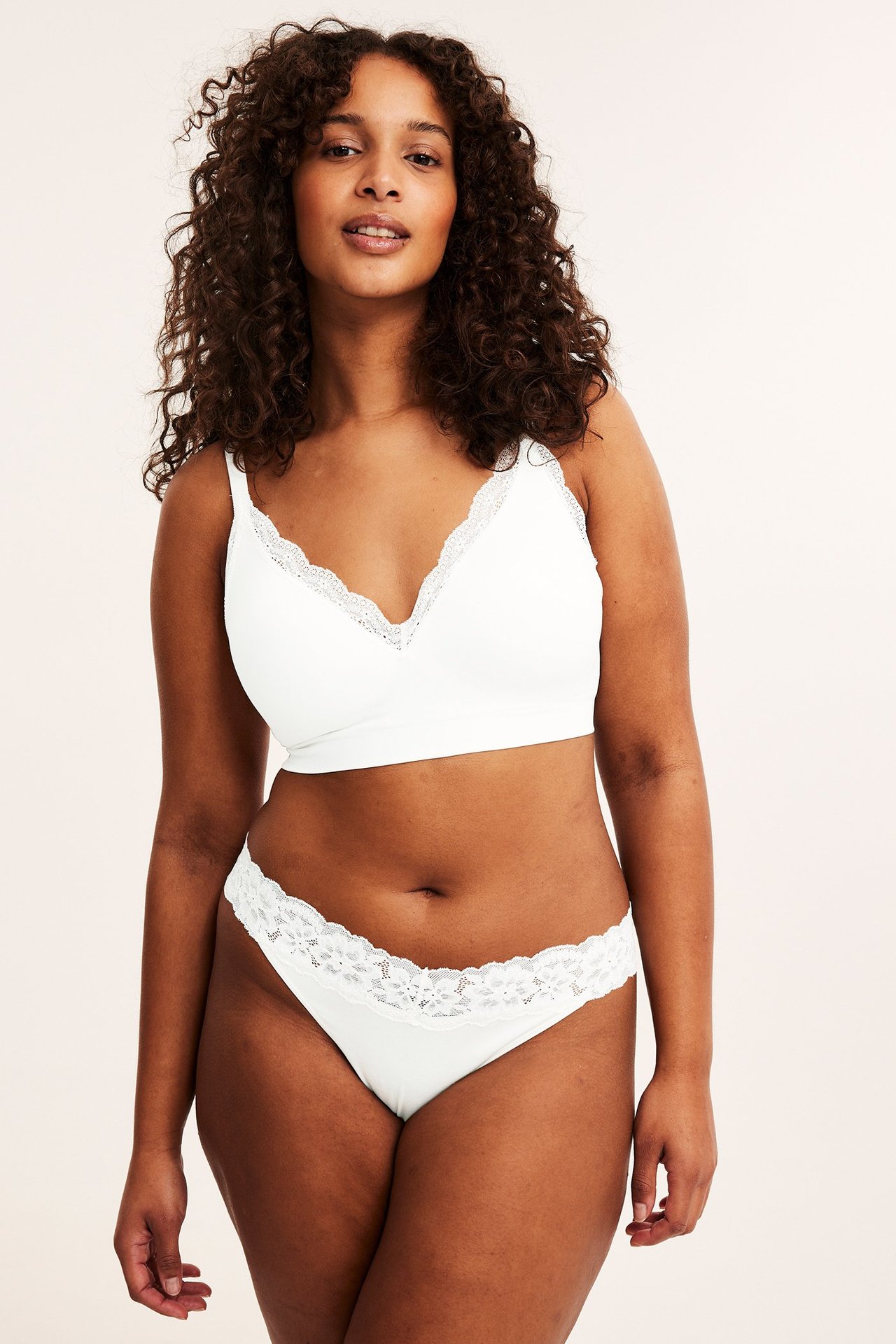 Forfra: kvinne i hvite lyocell stringtruser med blondekant og matchende hvit blondebralette.