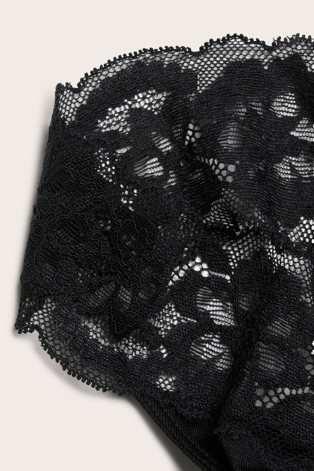 Lähikuva mustista pitsistringeistä, joissa näkyy monimutkaisia kukkakuvioita.