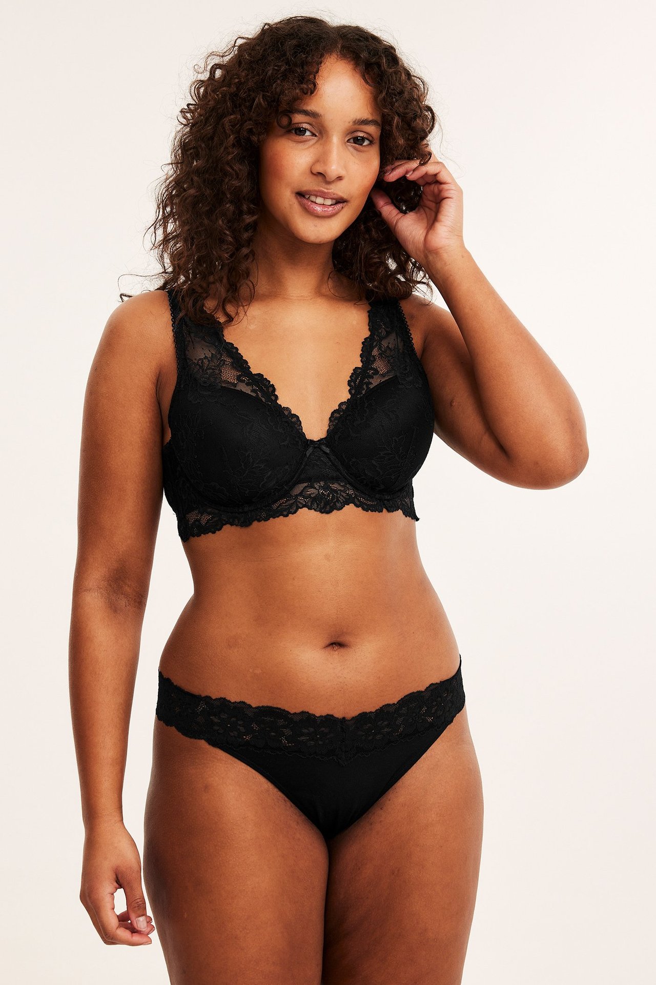 Forfra, kvinne i svart lyocell stringtruse med blondekant og matchende svart blonde-bh.