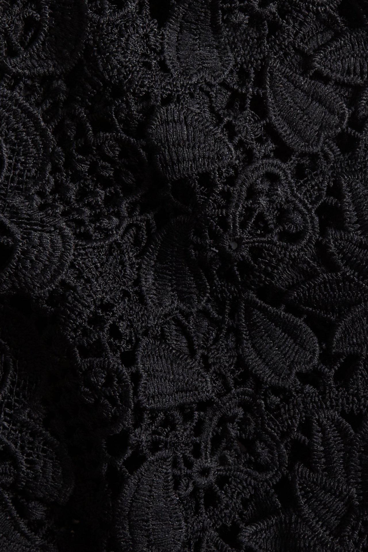 Zbliżenie czarnej koronki z detalicznym wzorem kwiatowym, wykonanej z poliestru.