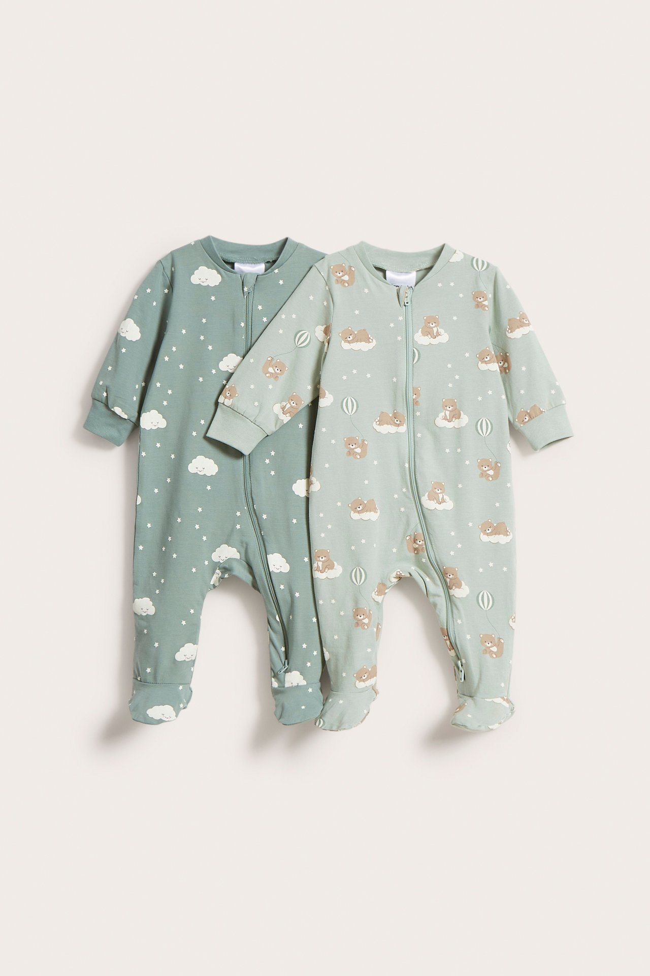 Framifrån: Två ljusgröna baby-pyjamasar med tvåvägsdragkedjor. En med moln/stjärnor, en med nallebjörnar.