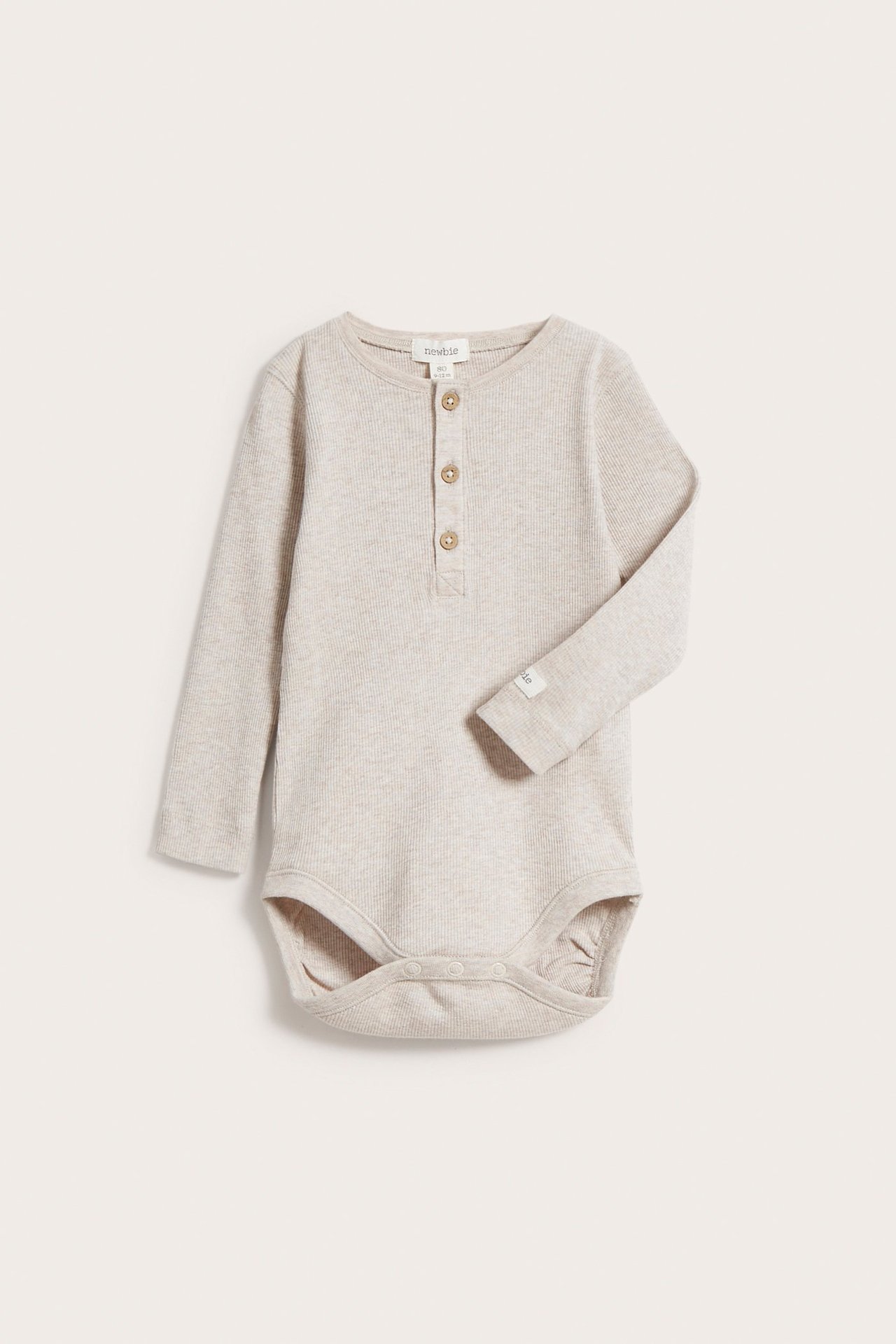 Frontvy av en baby beige melange ribbad långärmad body med knappslå och tryckknappar.