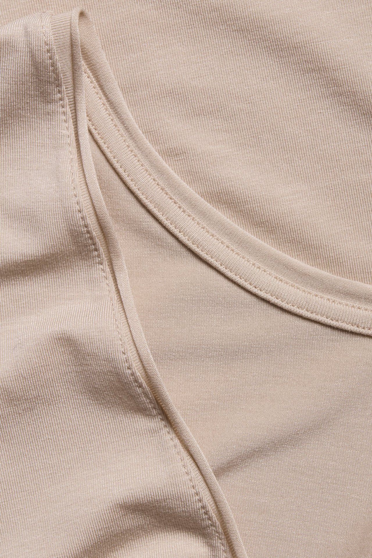 Zbliżenie beżowego topu z lyocellu z prążkowaną fakturą i dekoltem w serek.