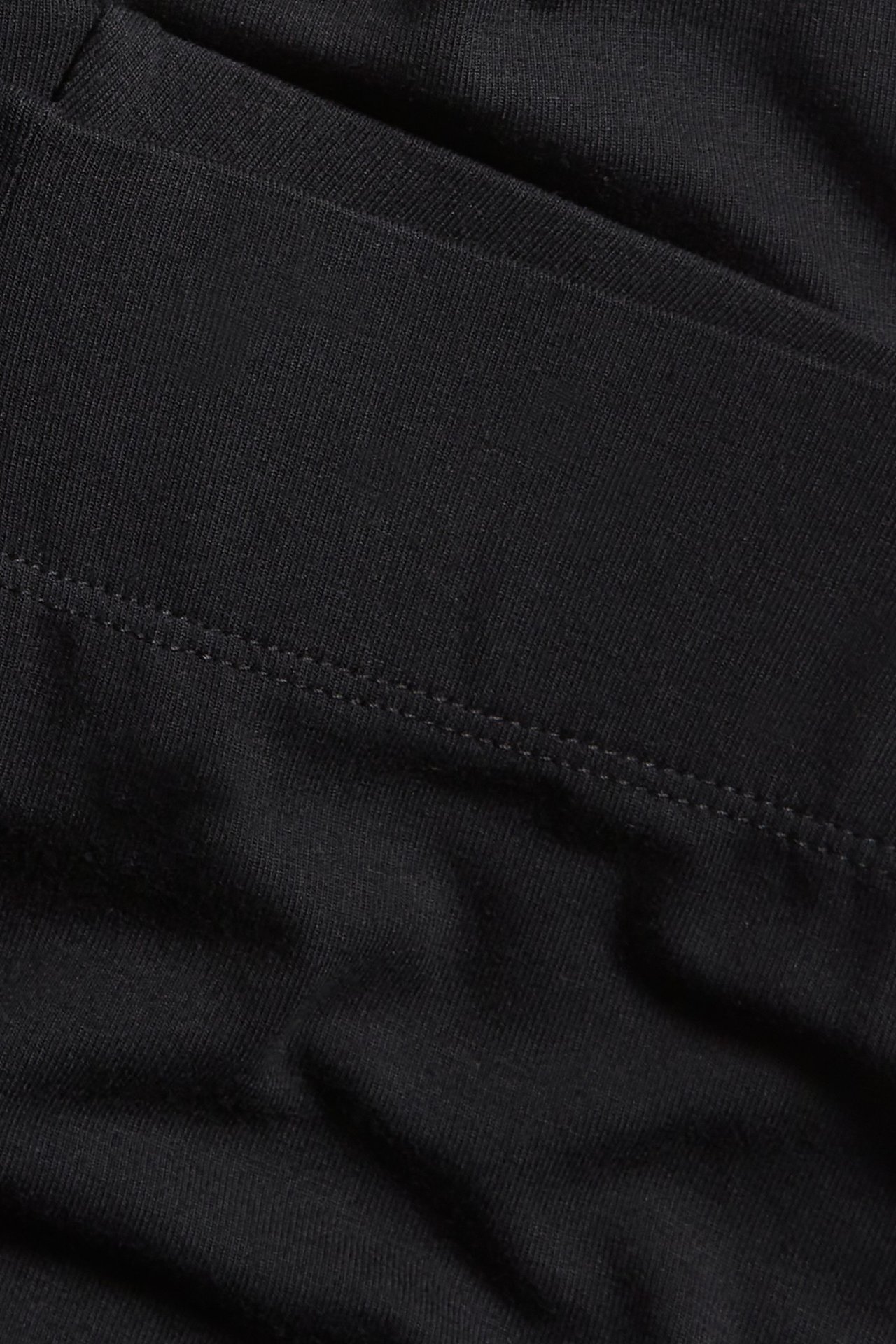 Zbliżenie na czarny, elastyczny materiał szortów capri z widocznymi szwami.