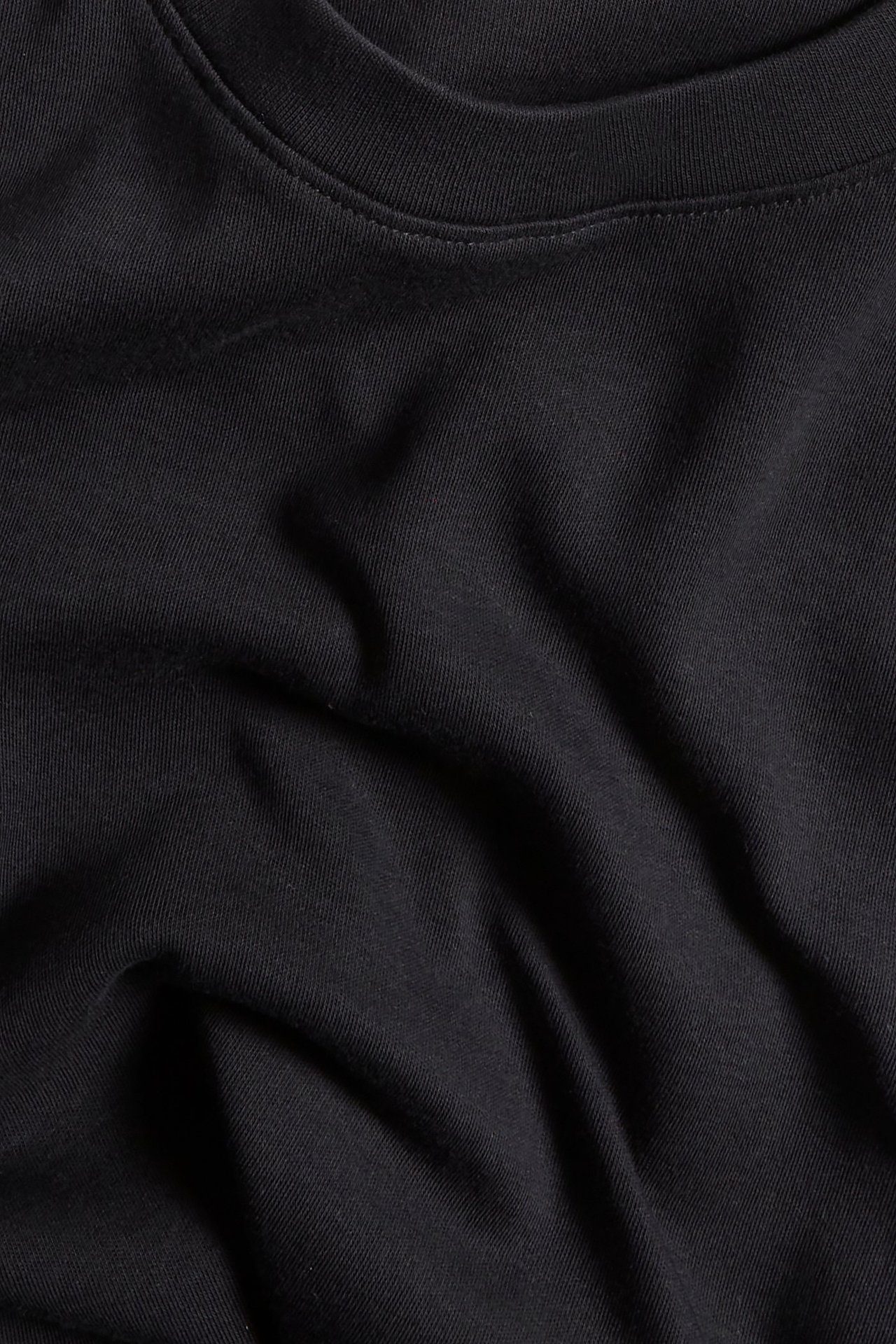 Zbliżenie czarnego, gładkiego, bawełnianego t-shirtu z długim rękawem i okrągłym dekoltem.