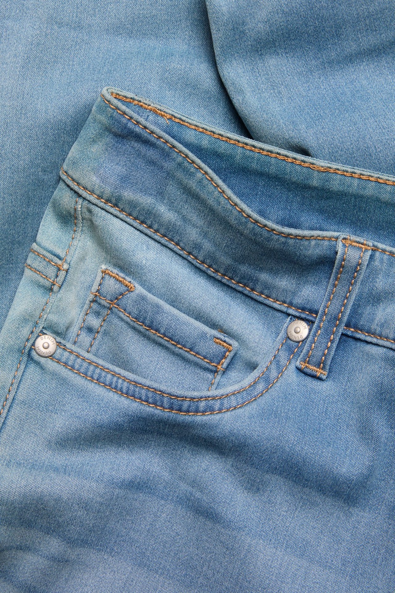 Lähikuva vaaleansinisistä denim super slim korkeavyötäröisistä farkuista, joissa näkyvät tikkaukset ja metalliniitti.
