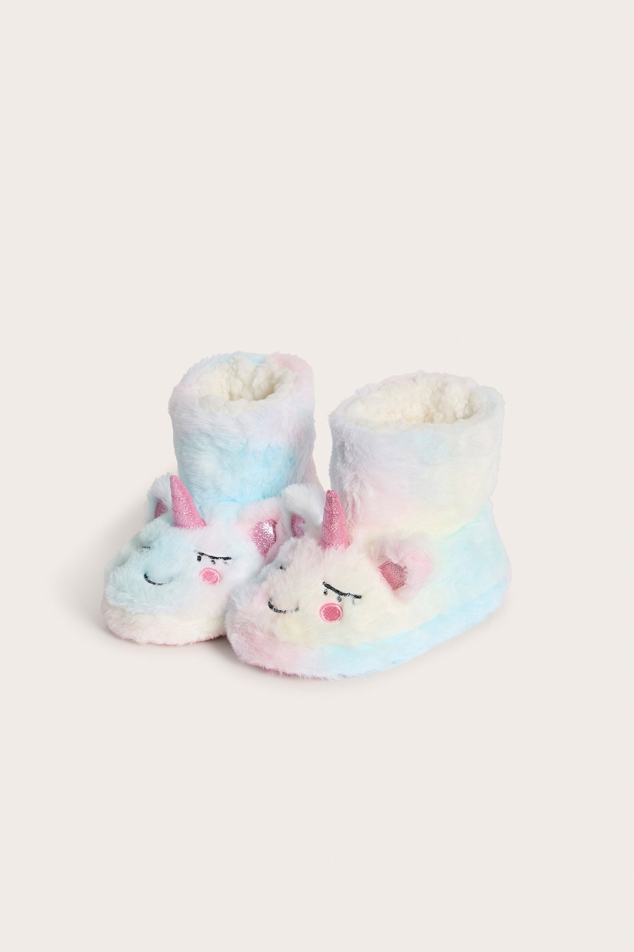 Widok z przodu: Dziecięce pastelowe tęczowe kapcie-botki z polaru jednorożca z różowymi rogami i puszystą podszewką.