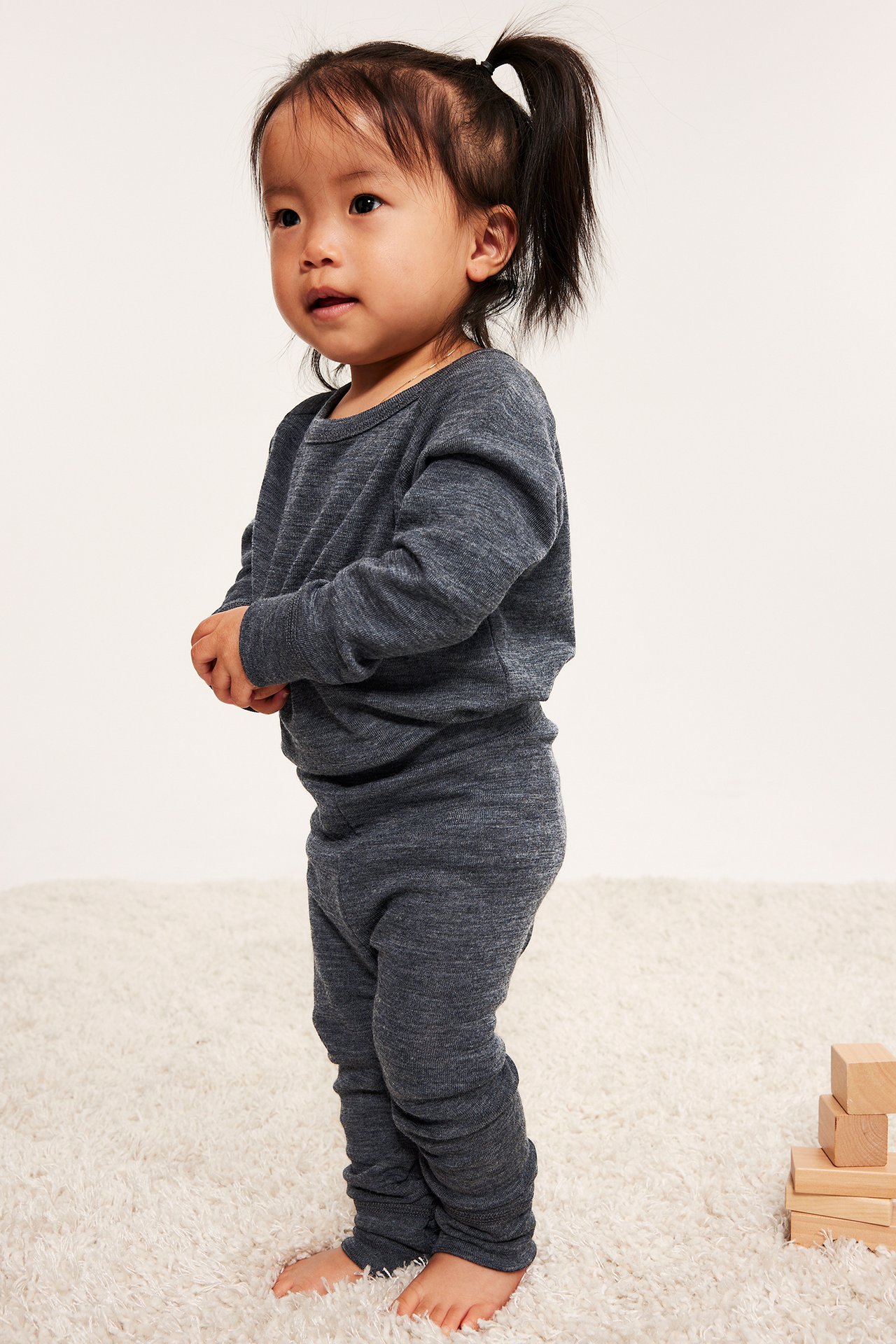 Widok z przodu na dziecko w ciemnoszarych melanżowych spodniach merino i pasującej bluzce.
