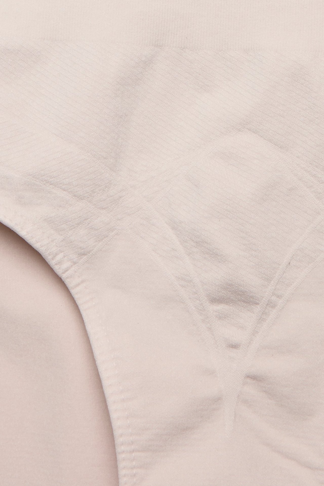 Zbliżenie na jasnobeżowe, bezszwowe figi modelujące z wysokim stanem i subtelnym wzorem.