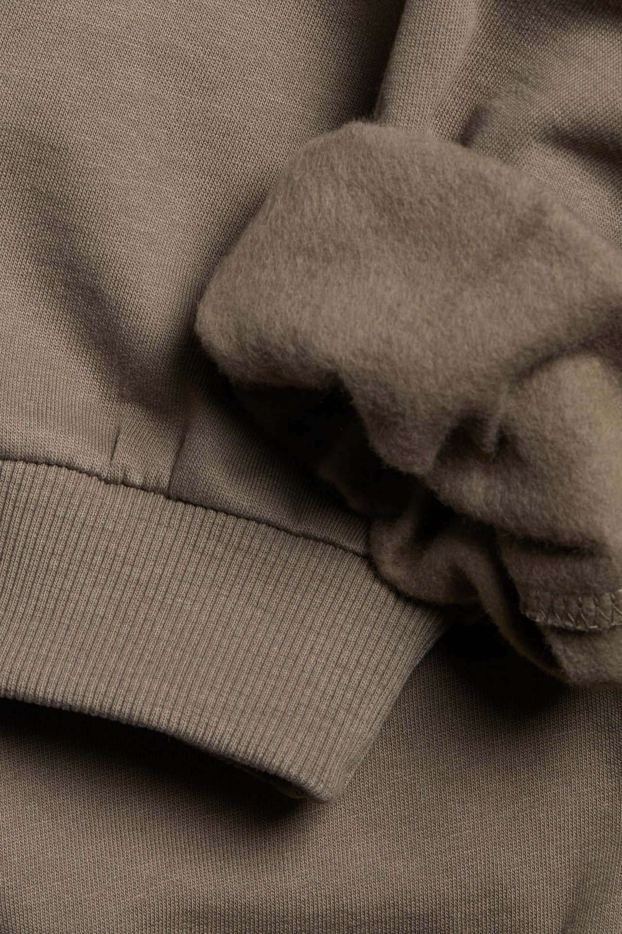 Zbliżenie brązowych bawełnianych spodni dresowych z prążkowanym ściągaczem i miękką podszewką.