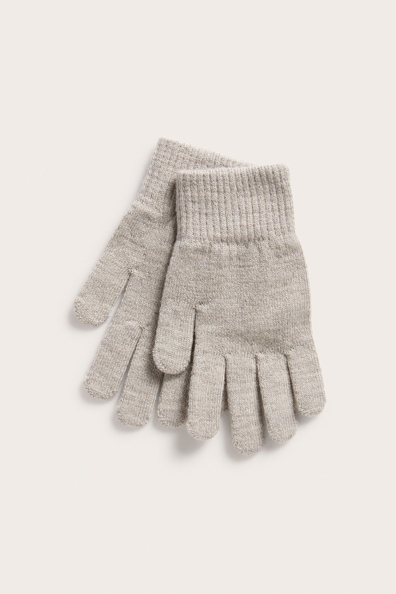Toppvy av ett par beigemelange fingervantar i ullmix med ribbade muddar, liggande platt.