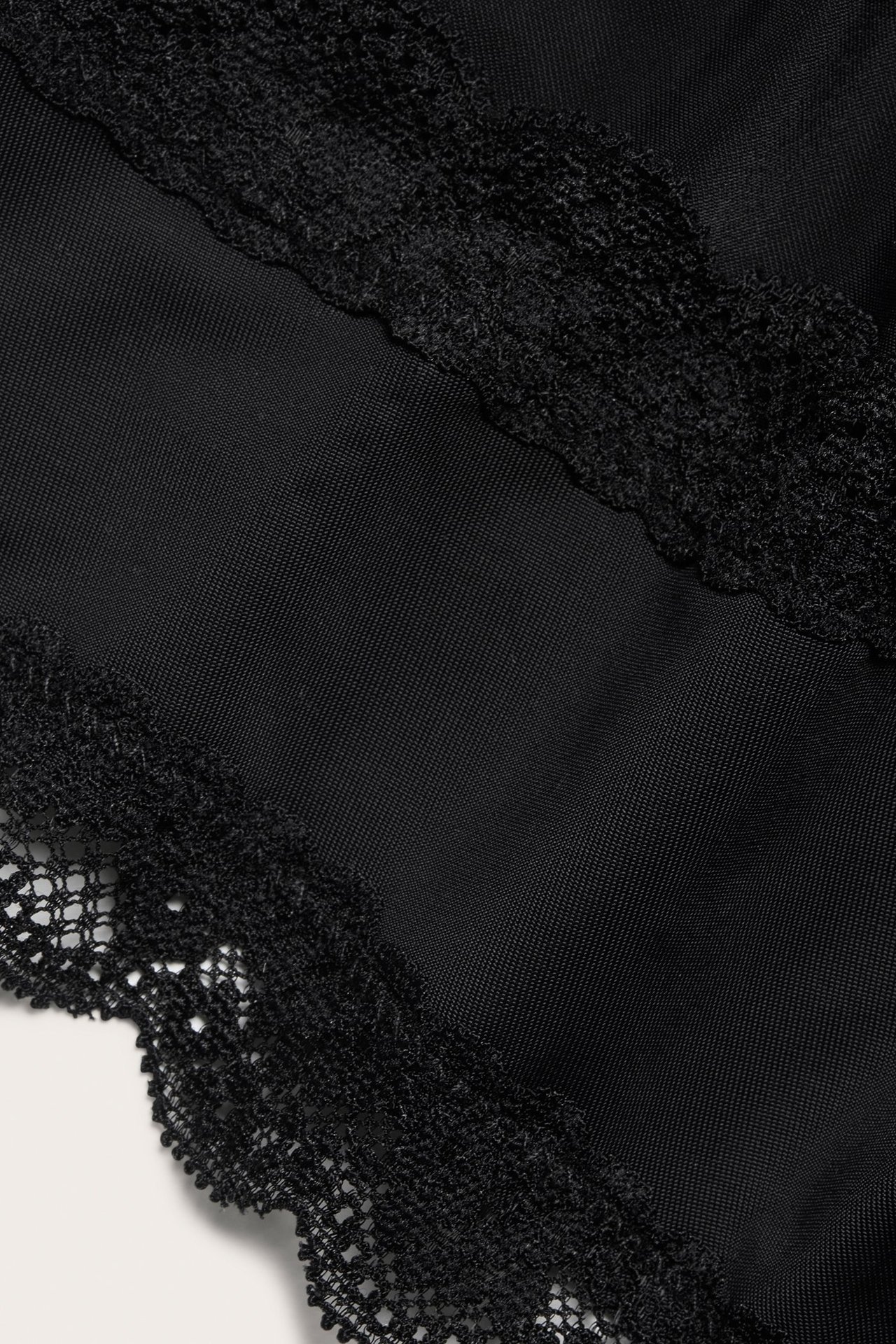 Zbliżenie czarnych fig cheeky z mikrofibry z koronkowym wykończeniem.