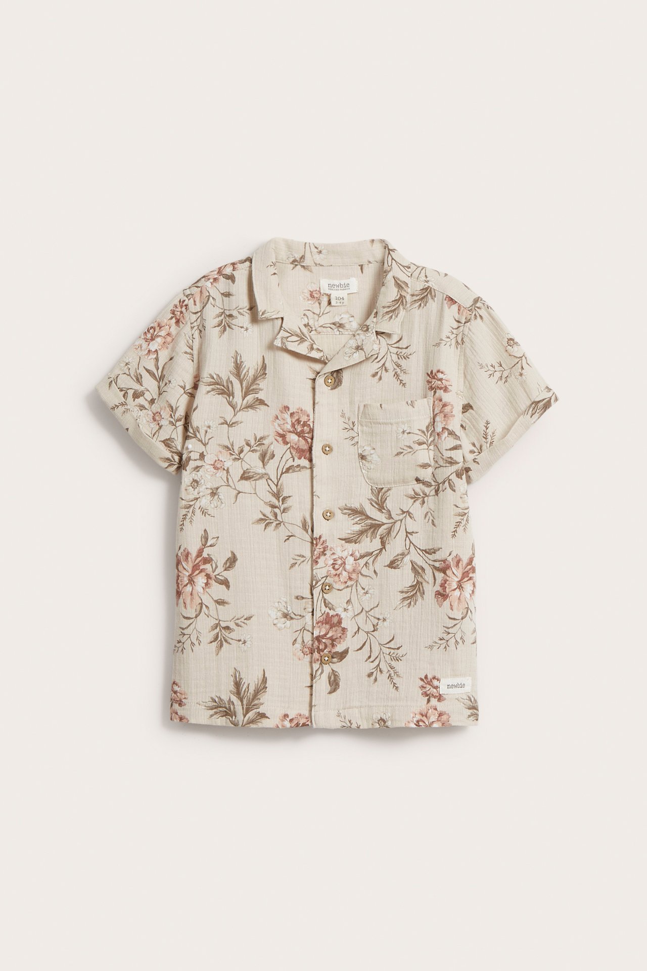Frontvy av en beige kortärmad bomullsskjorta med rosa och bruna blommönster, krage och knappar framtill.
