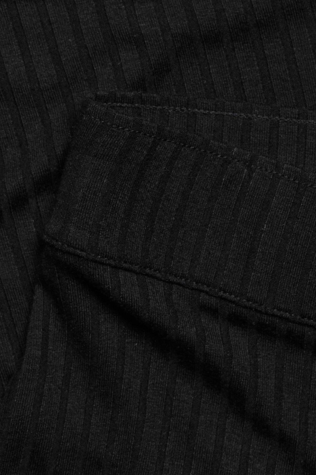 Zbliżenie czarnej prążkowanej spódnicy z mieszanki wiskozy z widocznymi szwami.