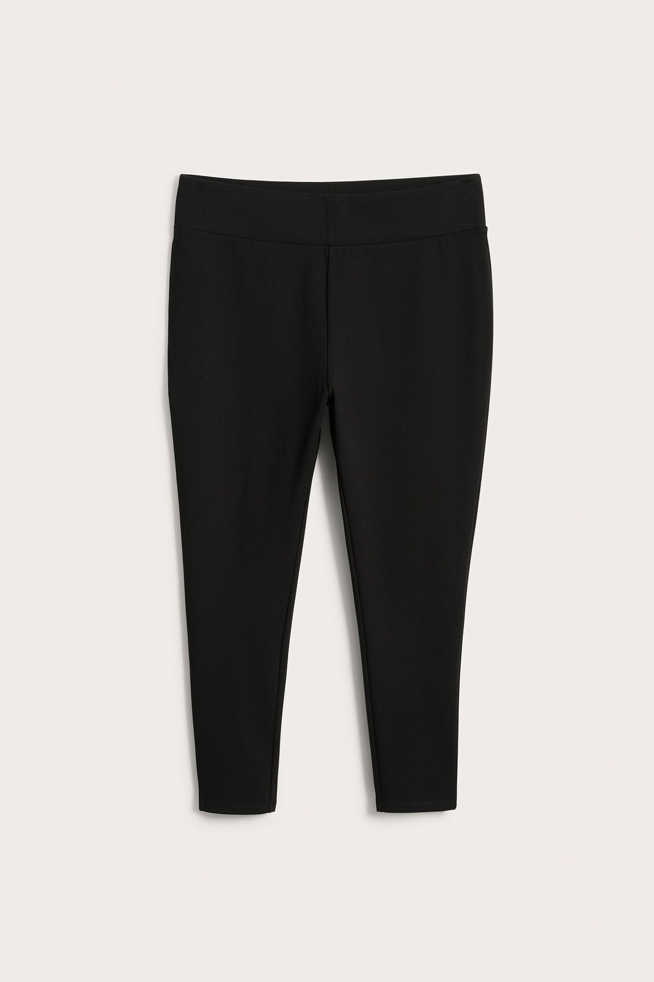 Edestä, mustat jersey-leggingsit leveällä joustovyötäröllä.