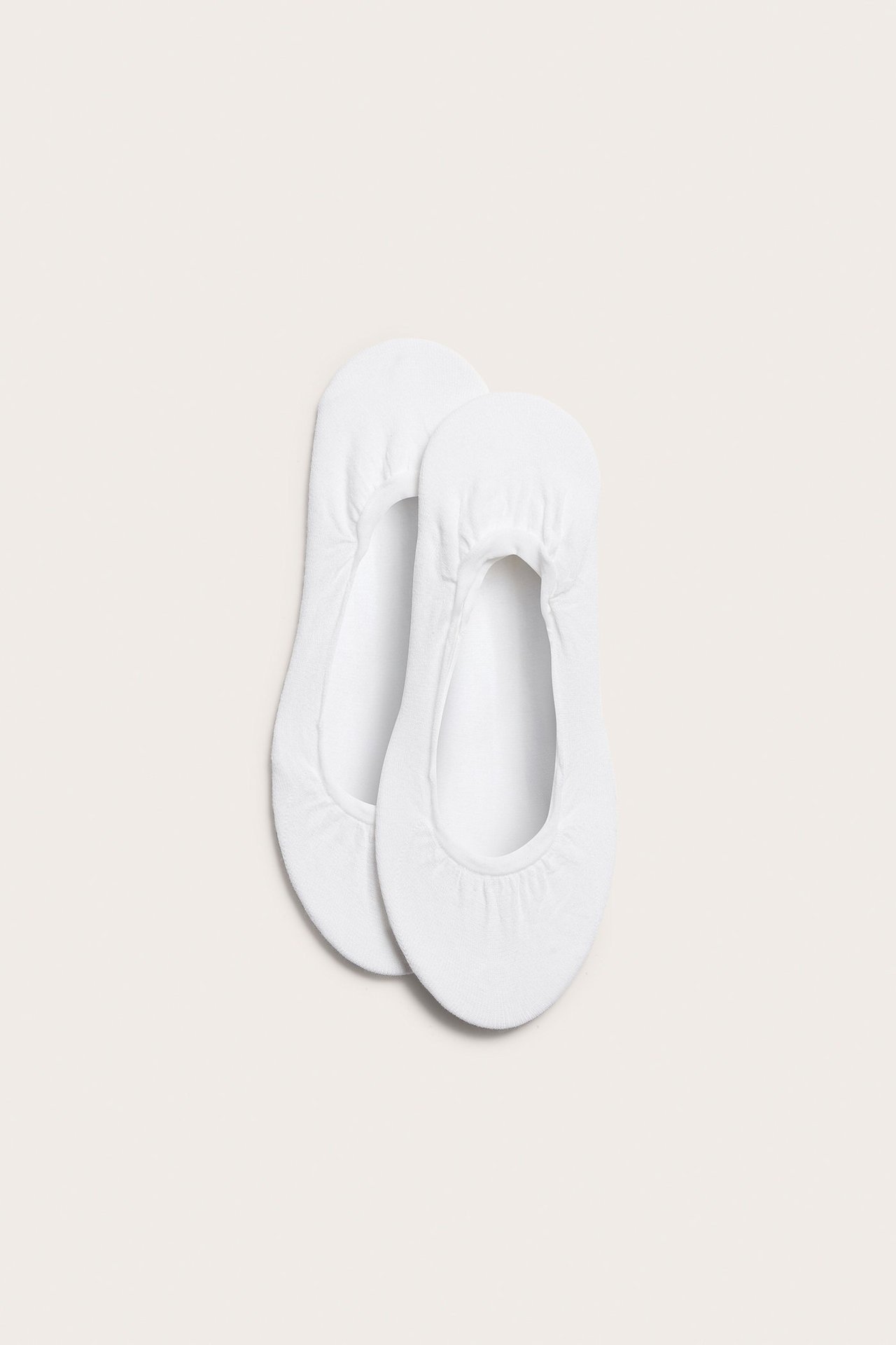 Ylhäältä kuvattuna kaksi yksiväristä valkoista puuvillasekoite ballerinatossua.