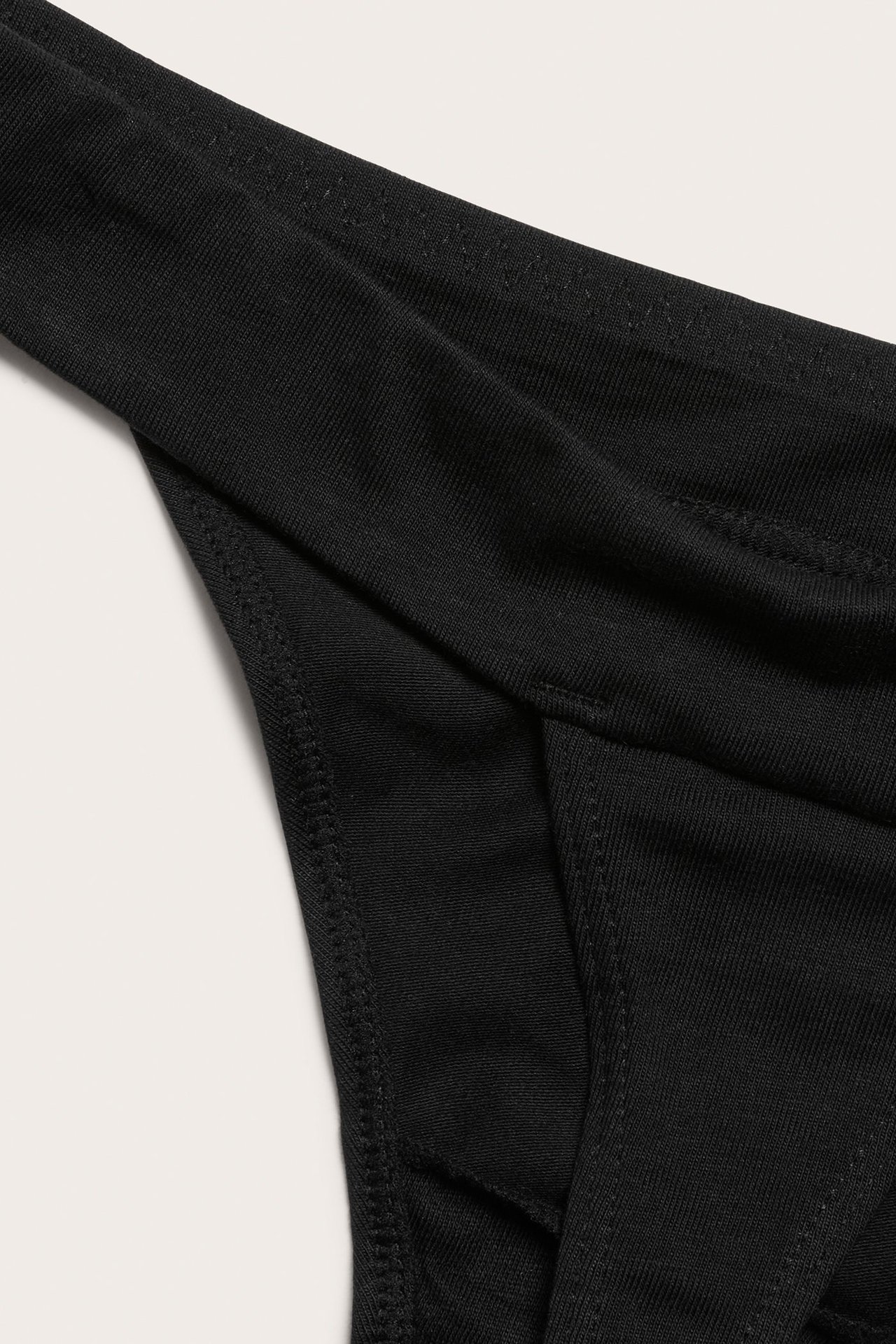 Zbliżenie na czarne, jednolite stringi z mieszanki bawełny z widocznymi szwami.