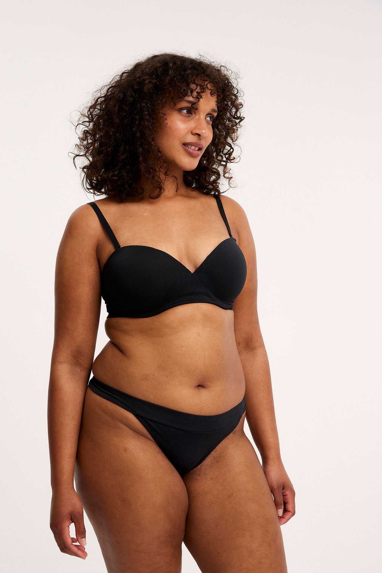 Forfra, kvinne i svart stringtruse i bomullsblanding og matchende svart BH.