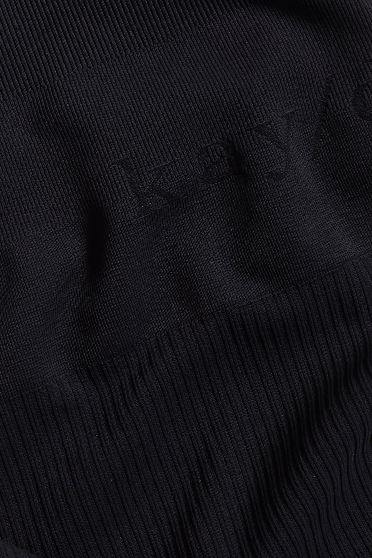 Lähikuva mustista saumattomista ribatuista pyöräilyshortseista, joissa on hienovarainen 'kay/day'-logo.