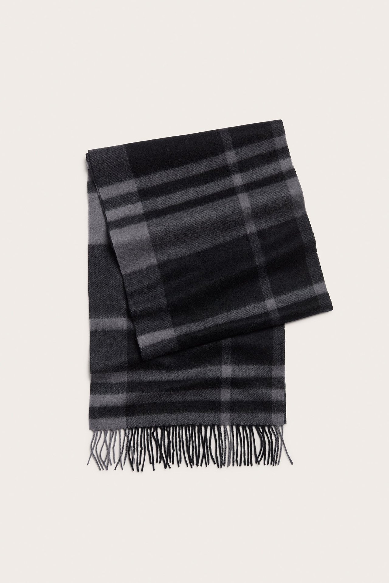 Widok z góry na złożony czarno-ciemnoszary wełniany szalik w kratę z frędzlami.