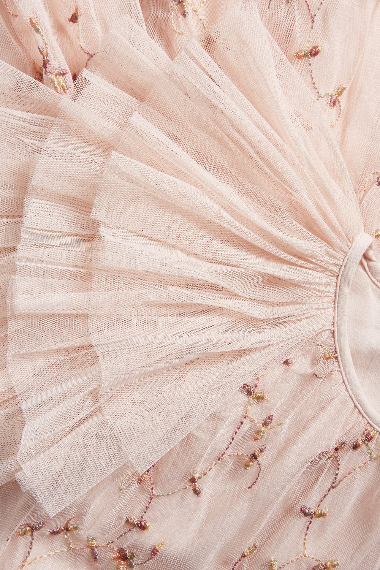 Zbliżenie jasnoróżowej sukienki z siateczki z wielobarwnym haftem kwiatowym i warstwowymi falbanami.