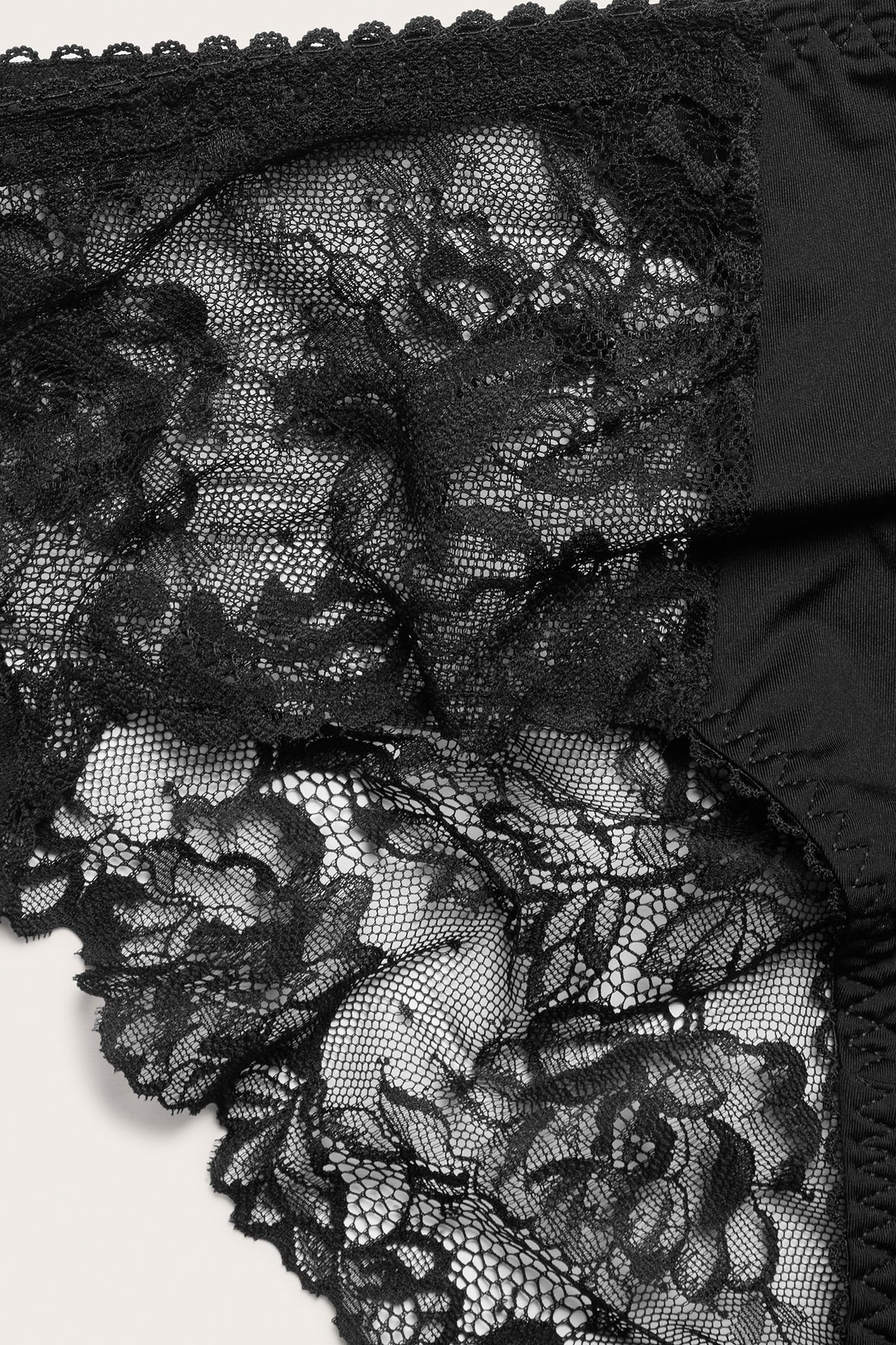 Zbliżenie czarnych koronkowych fig z kwiatowym wzorem i jednolitym detalem z tkaniny.