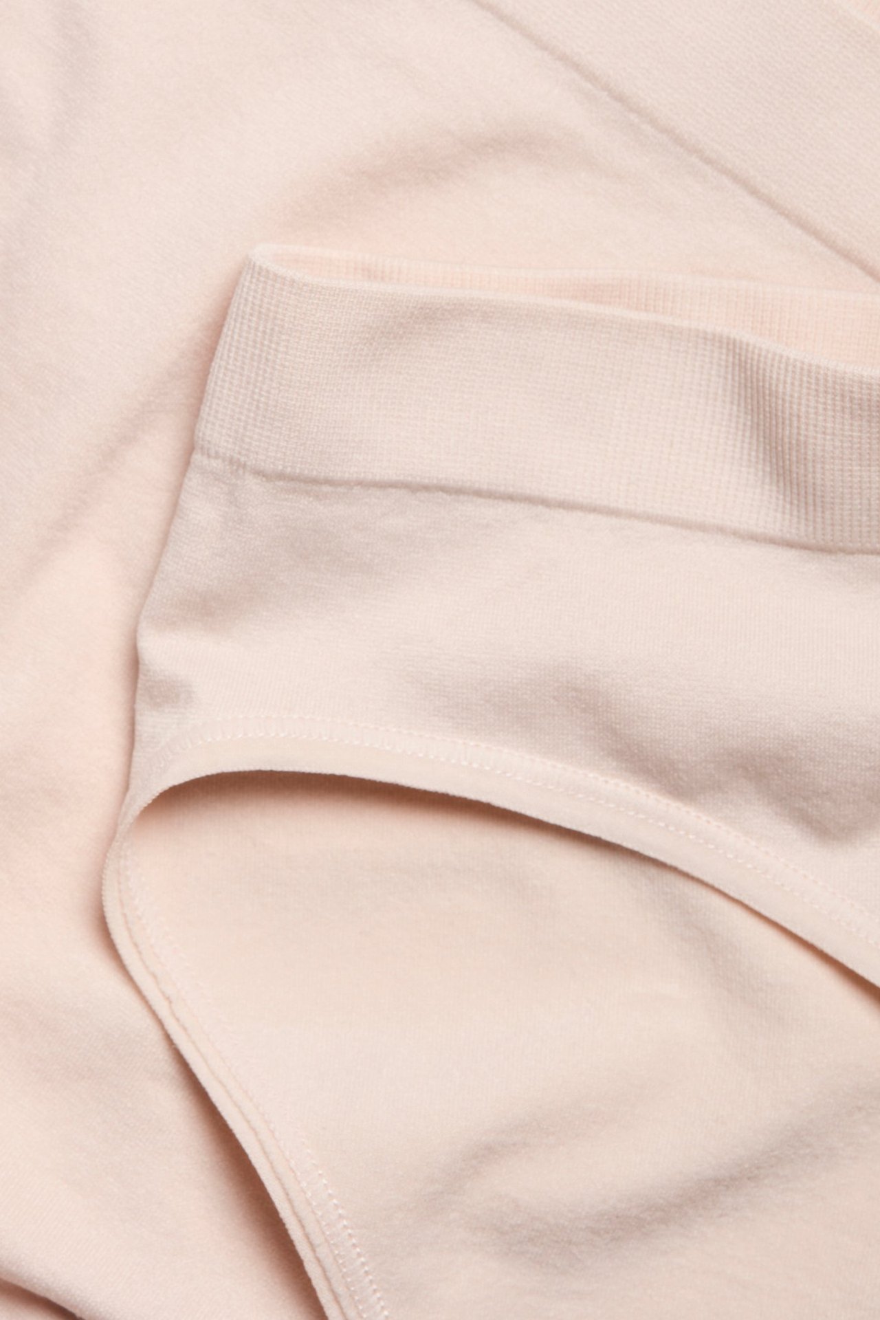 Zbliżenie na jasnoróżowe figi z prążkowanym pasem, wykonane z miękkiego, jednolitego materiału.