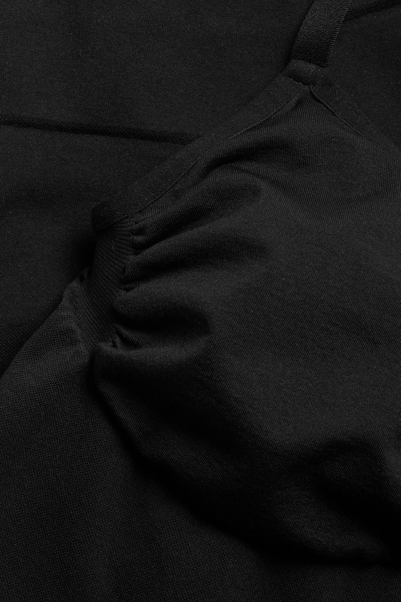 Zbliżenie czarnego, bezszwowego body modelującego z regulowanym ramiączkiem i marszczonym detalem.