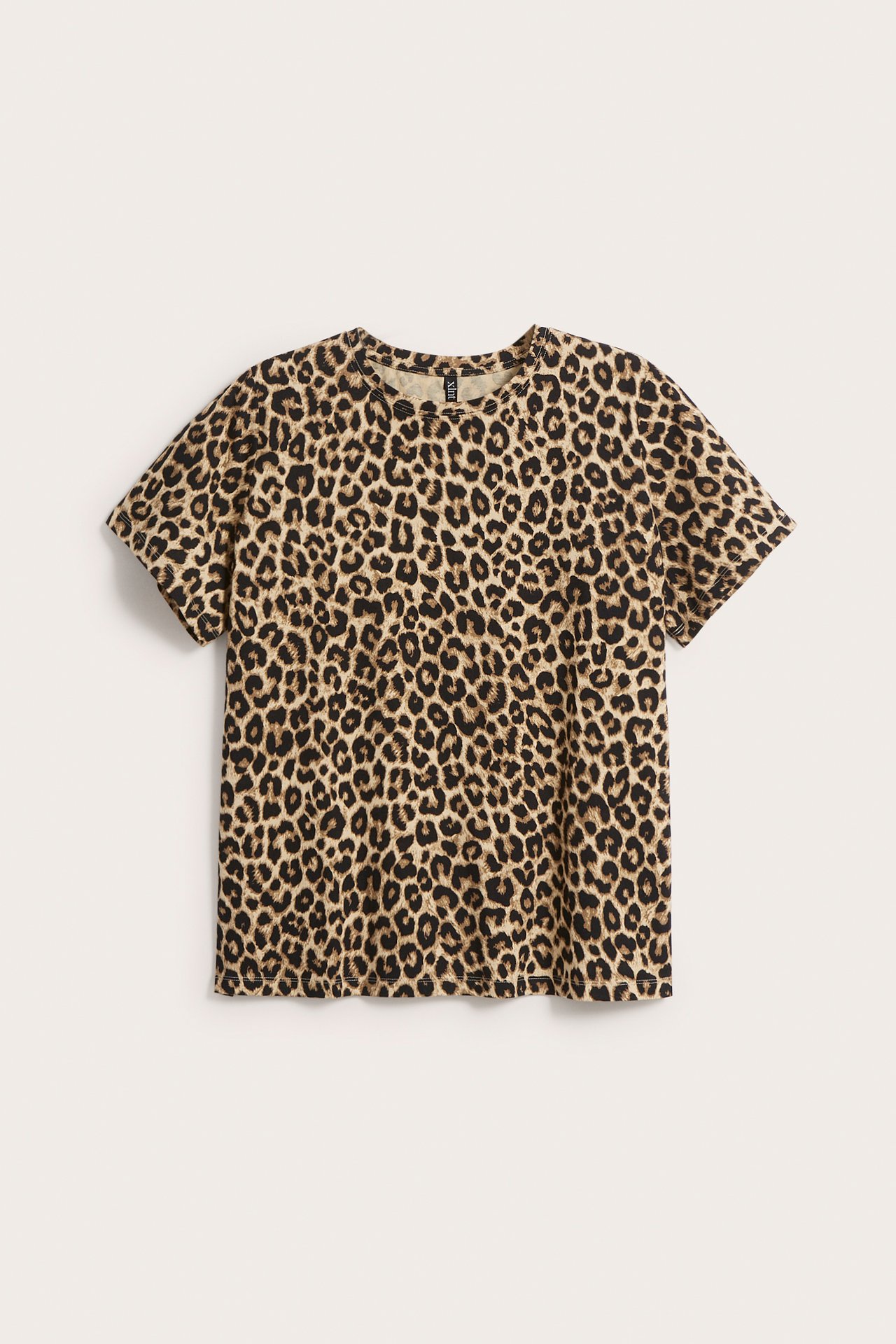 Framsida av en beige kortärmad t-shirt med leopardmönster.