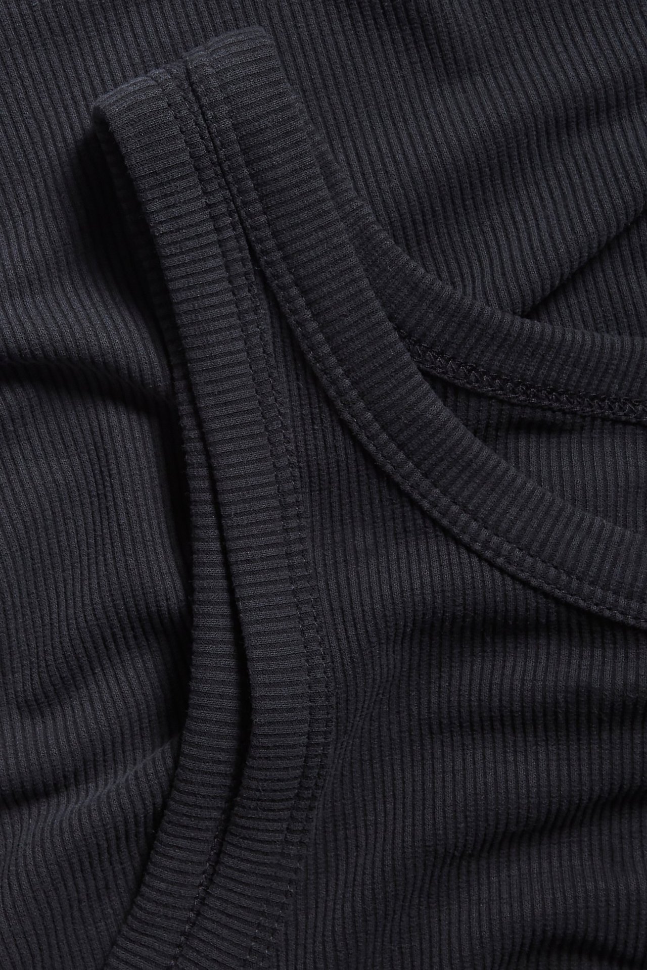 Zbliżenie czarnego prążkowanego topu z mieszanki modalu, ukazujące fakturę materiału i szwy.